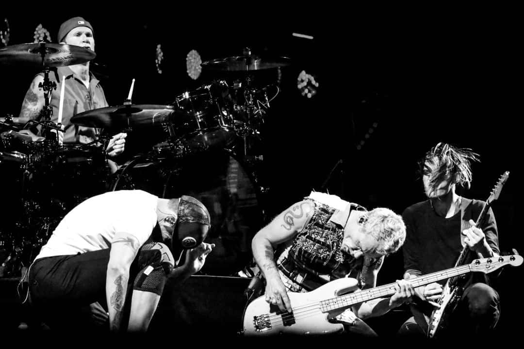 Rock 桌布 壁紙 — 三位音樂家在黑暗舞台上激烈演奏鼓、貝斯和吉他的黑白照片。