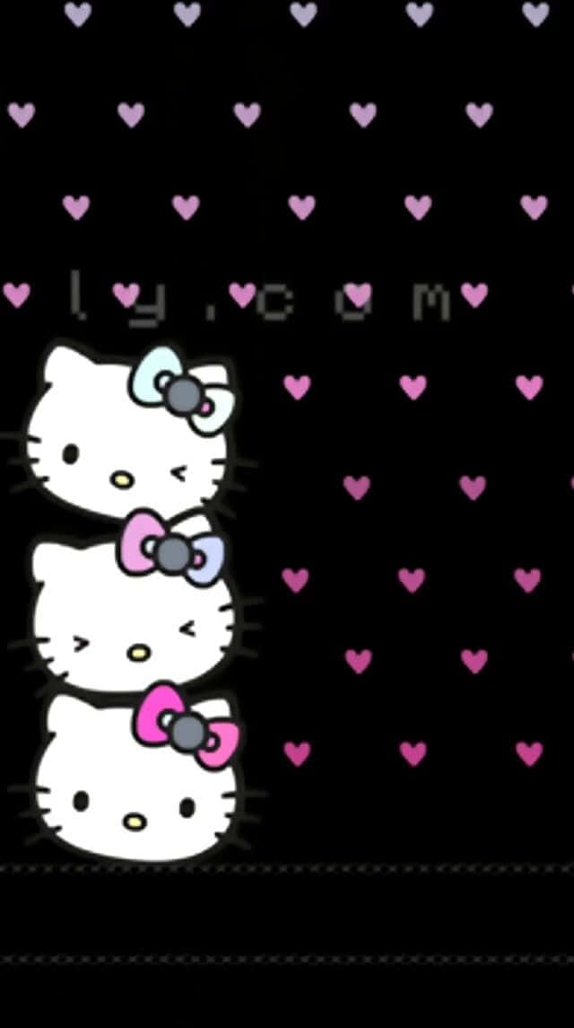 Emo Hello Kitty 桌布 壁紙 — 三個Hello Kitty面孔疊在一起，帶著彩色蝴蝶結，漂浮在灑滿粉紅色心形的黑色背景上。