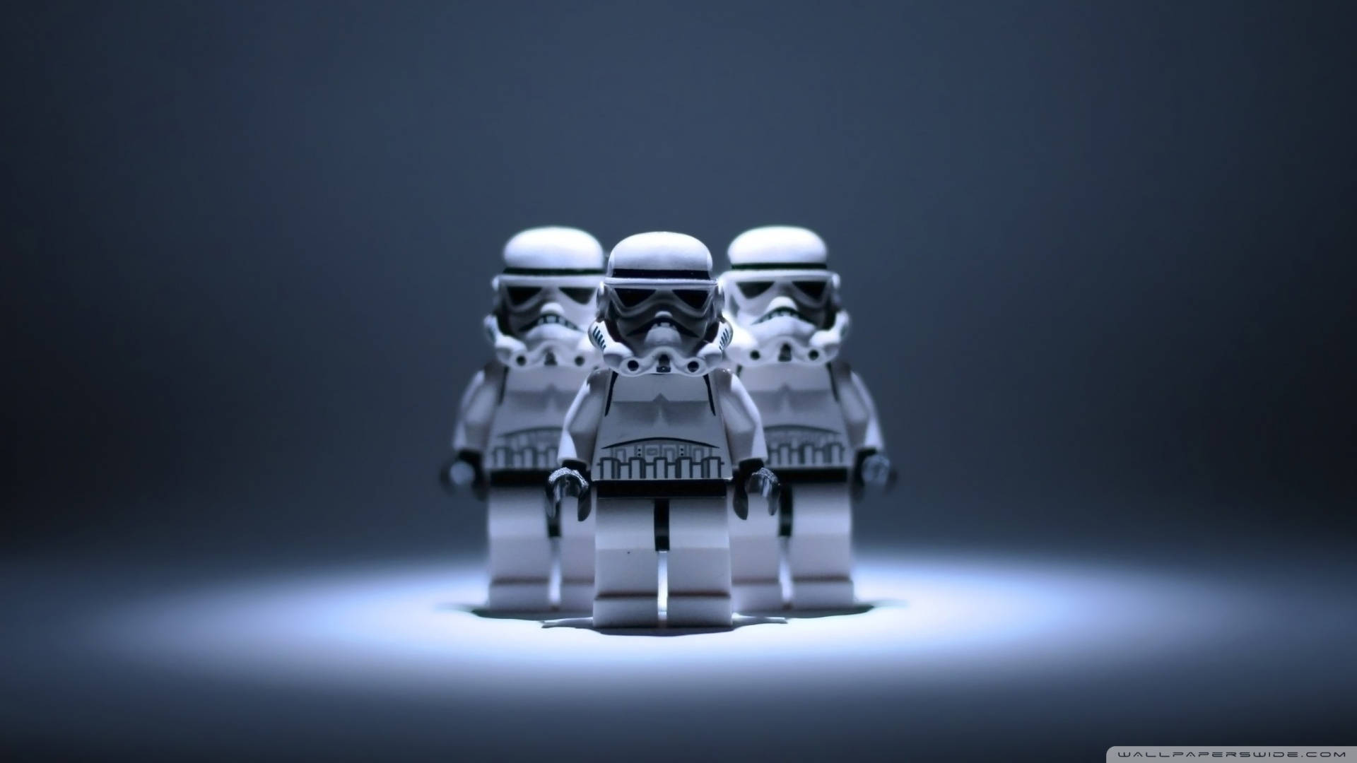 星際大戰 桌布 壁紙 — 三個LEGO風暴兵站在聚光燈下，以深色漸層背景搭配戲劇性燈光。
