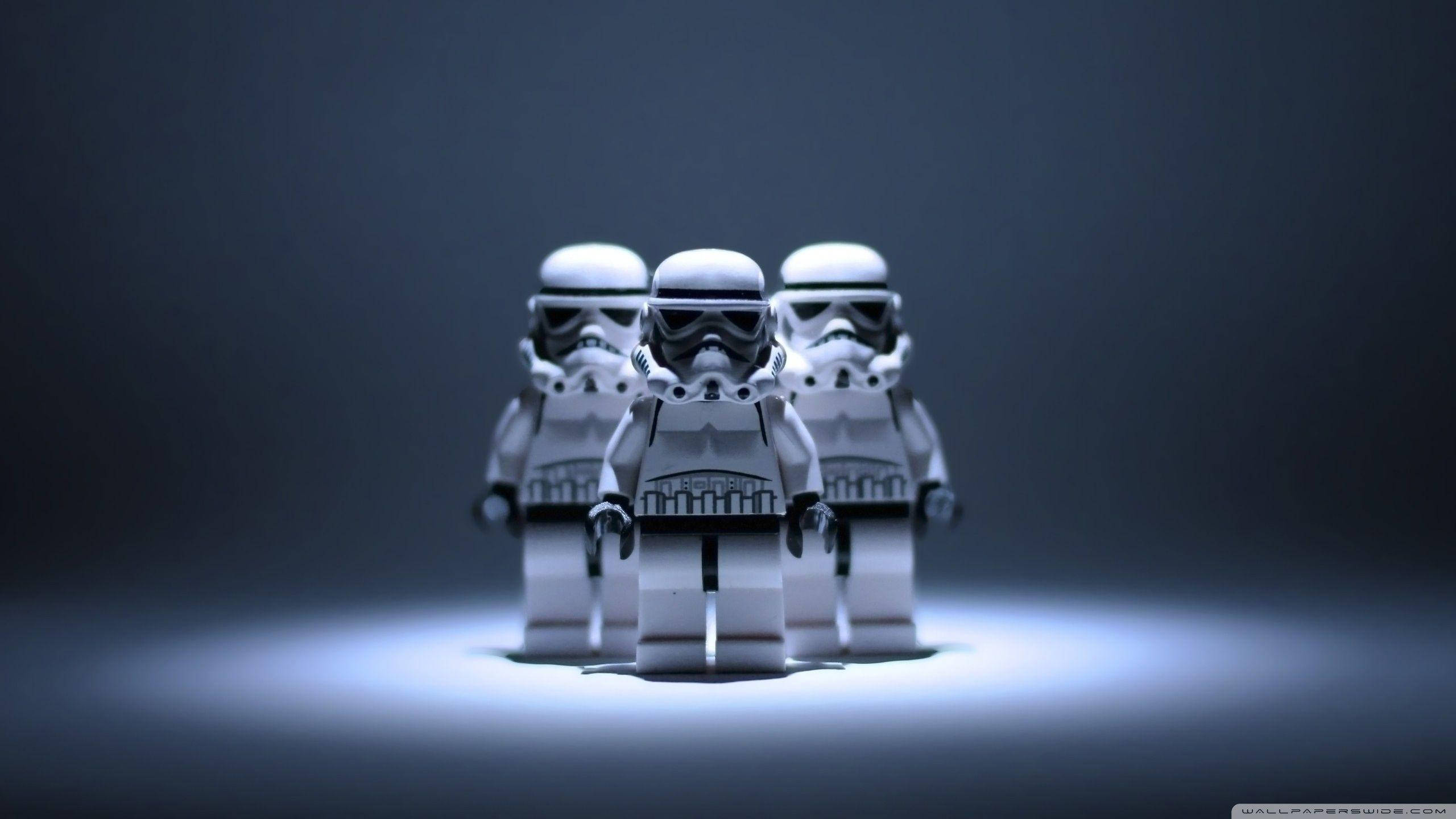 星際大戰 桌布 壁紙 — 三個LEGO風暴兵站在聚光燈下，背景為深灰色，帶有戲劇性的燈光效果。