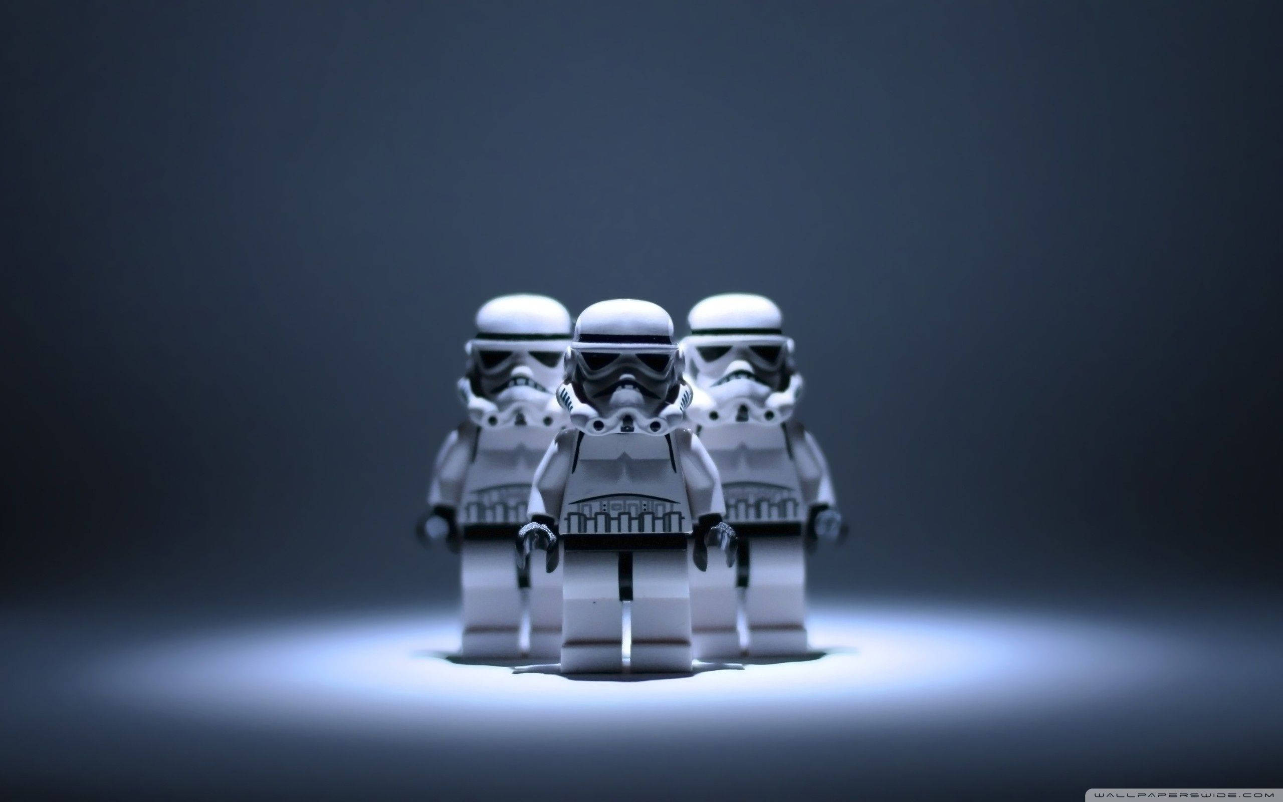 樂高 桌布 壁紙 — 三個LEGO風暴兵站在聚光燈下，背景為深色漸變，帶有戲劇性的燈光效果。