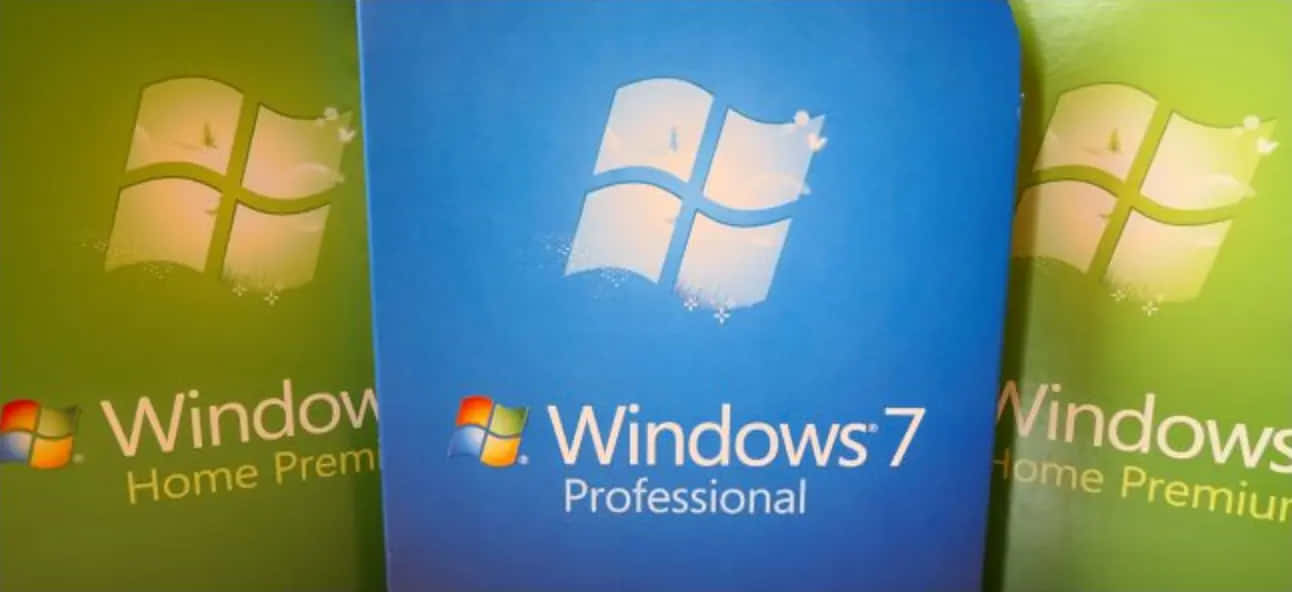 Windows 7 桌布 壁紙 — 三個Windows 7軟體盒，藍色和綠色封面，帶有標誌性視窗標誌和產品名稱。