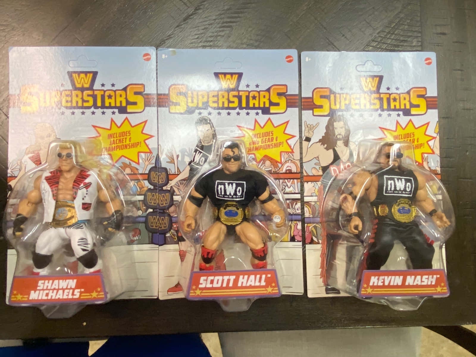 toys 桌布 壁紙 — 三個WWE超級巨星人偶，原裝包裝，放在深色木質表面上。