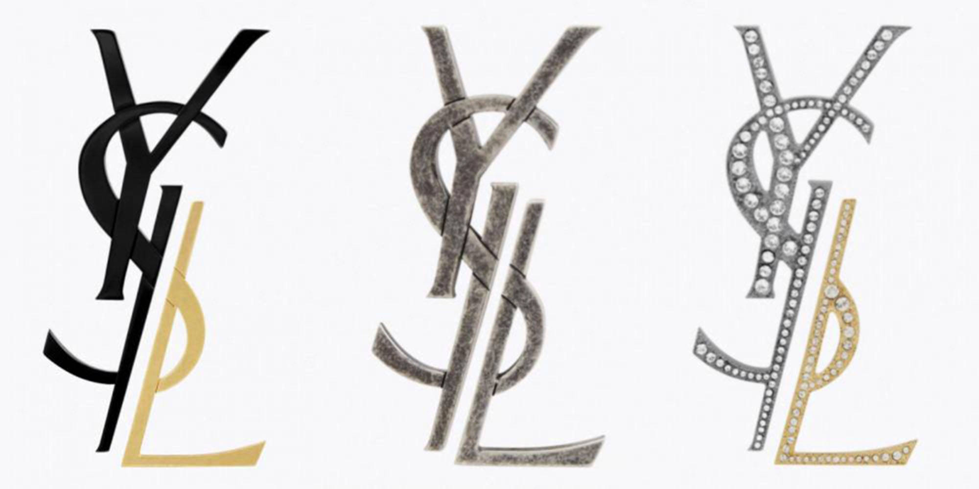 Ysl 桌布 壁紙 — 三個YSL標誌以黑色金色金屬和鑲鑽風格並排顯示在白色背景上。