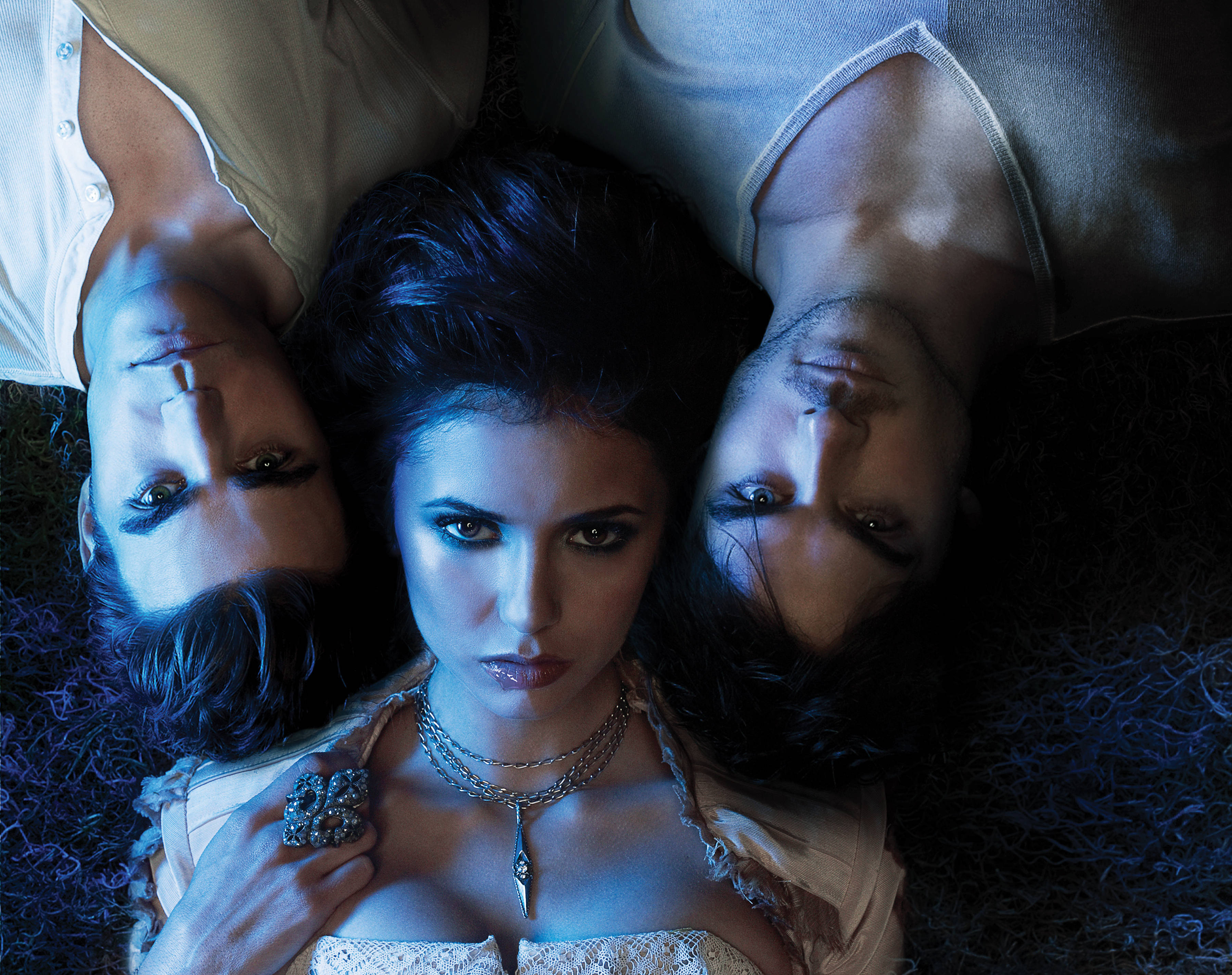 The Vampire Diaries 桌布 壁紙 — 三個人以三角形排列躺在草地上，在冷藍色燈光下，目光強烈地向上凝視。