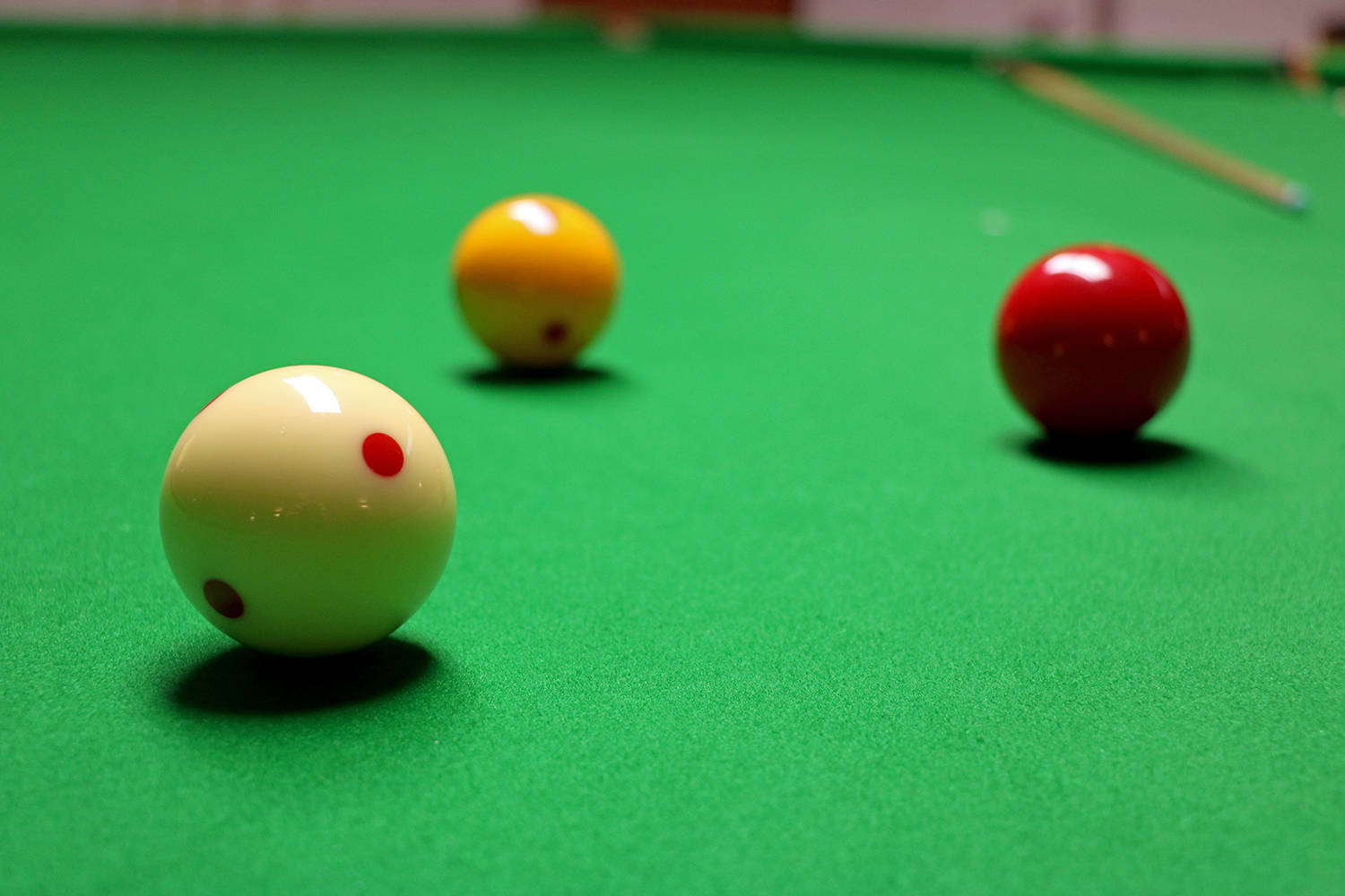balls 桌布 壁紙 — 三個光澤的撞球放在鮮綠色絨布桌上，背景中有一支模糊的球桿。