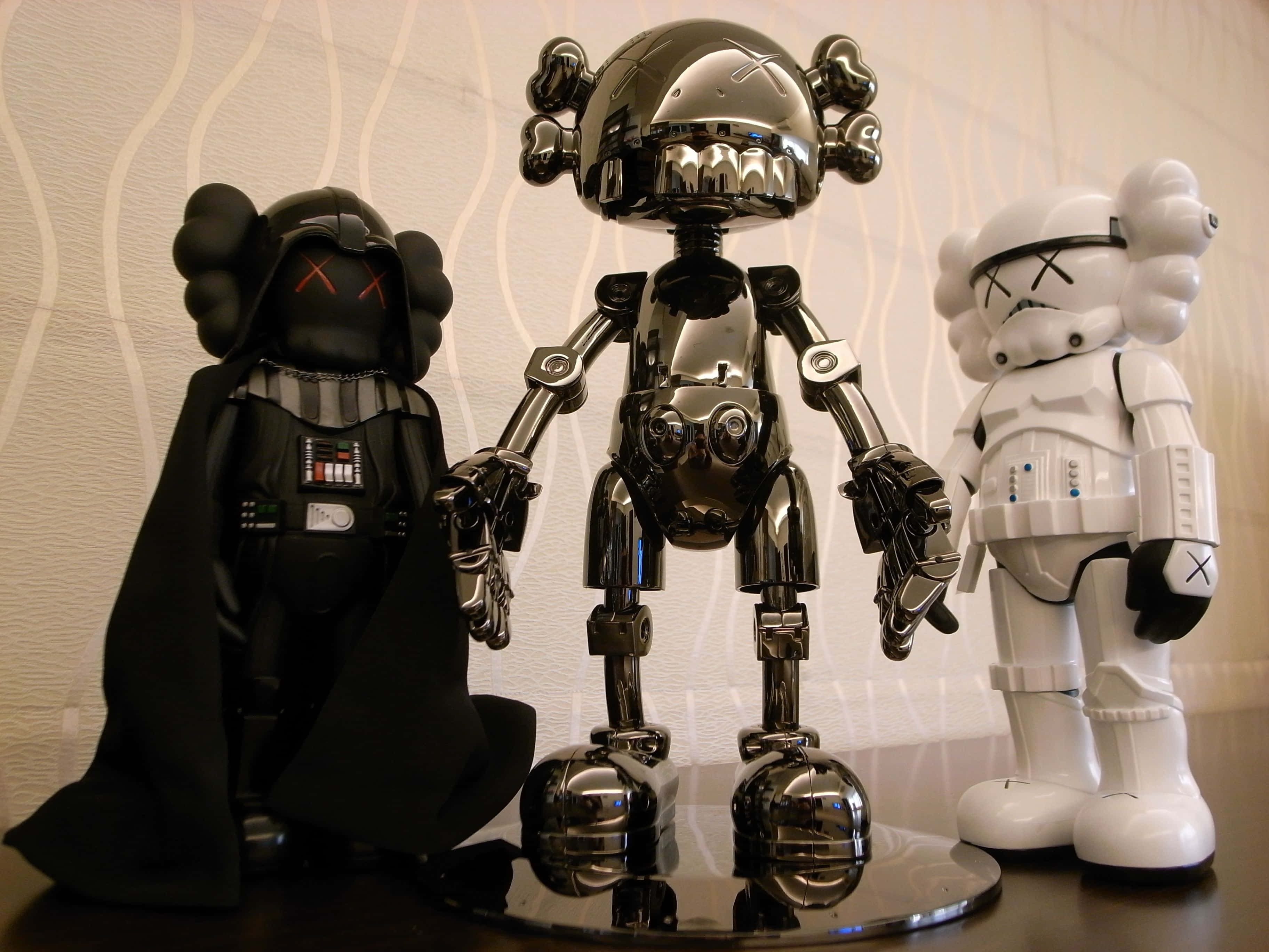 Kaws Stormtrooper 桌布 壁紙 — 三個光面KAWS x Star Wars收藏級人偶：黑武士、風暴兵及鉻機械人，立於反光底座上，背景為波浪紋壁紙。