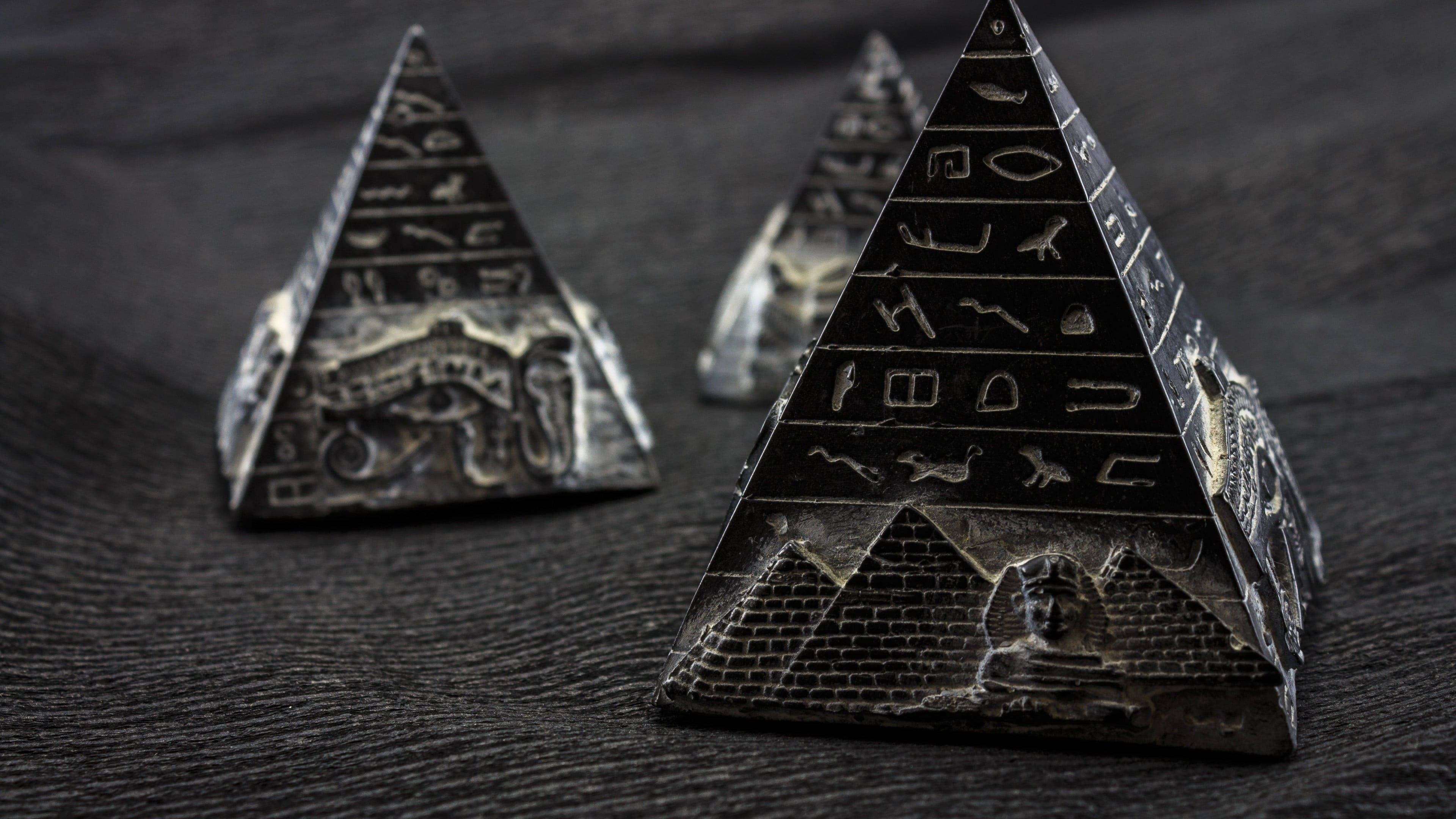 pyramid 桌布 壁紙 — 三個刻有象形文字和獅身人面像的精緻微型金字塔，放置在深色紋理表面上。