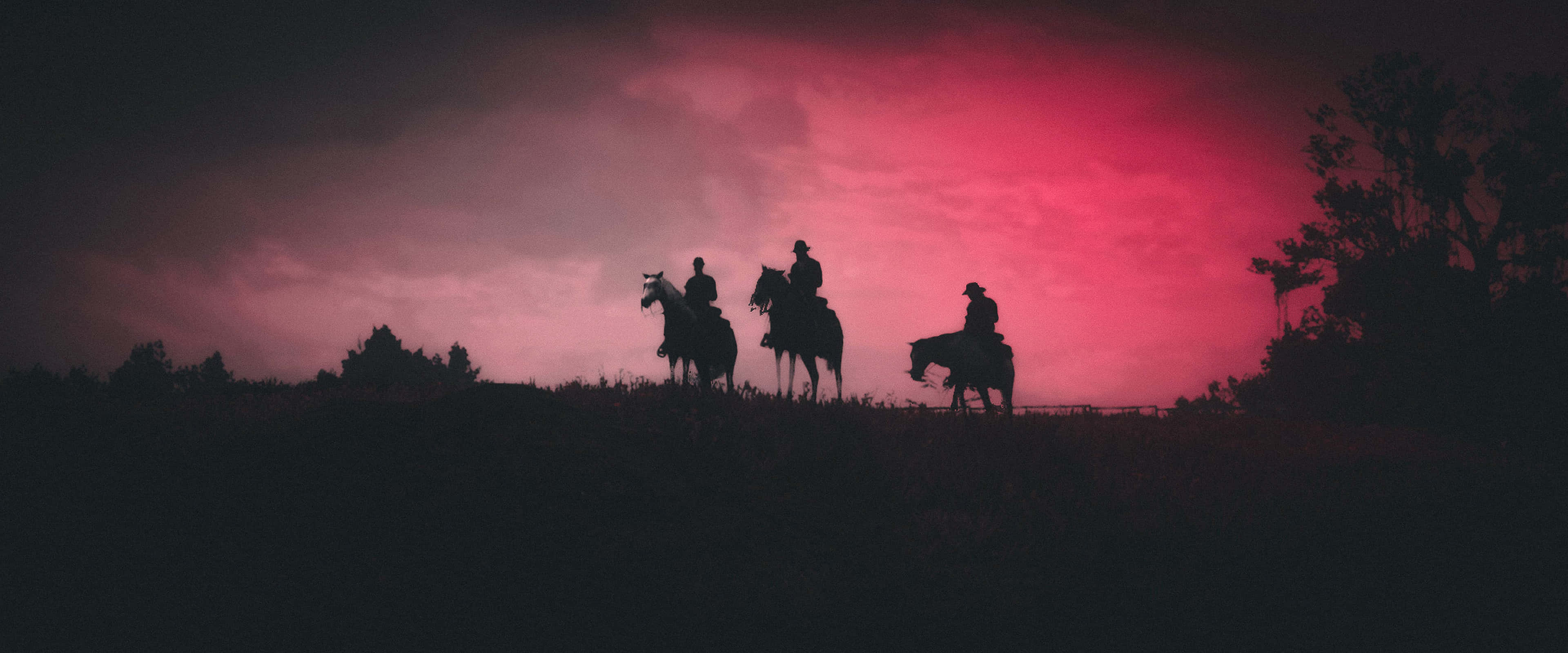 Red Dead Redemption 4K 桌布 壁紙 — 三個剪影騎手騎在馬背上，站在山丘上，背景是戲劇性的血紅色黃昏天空。