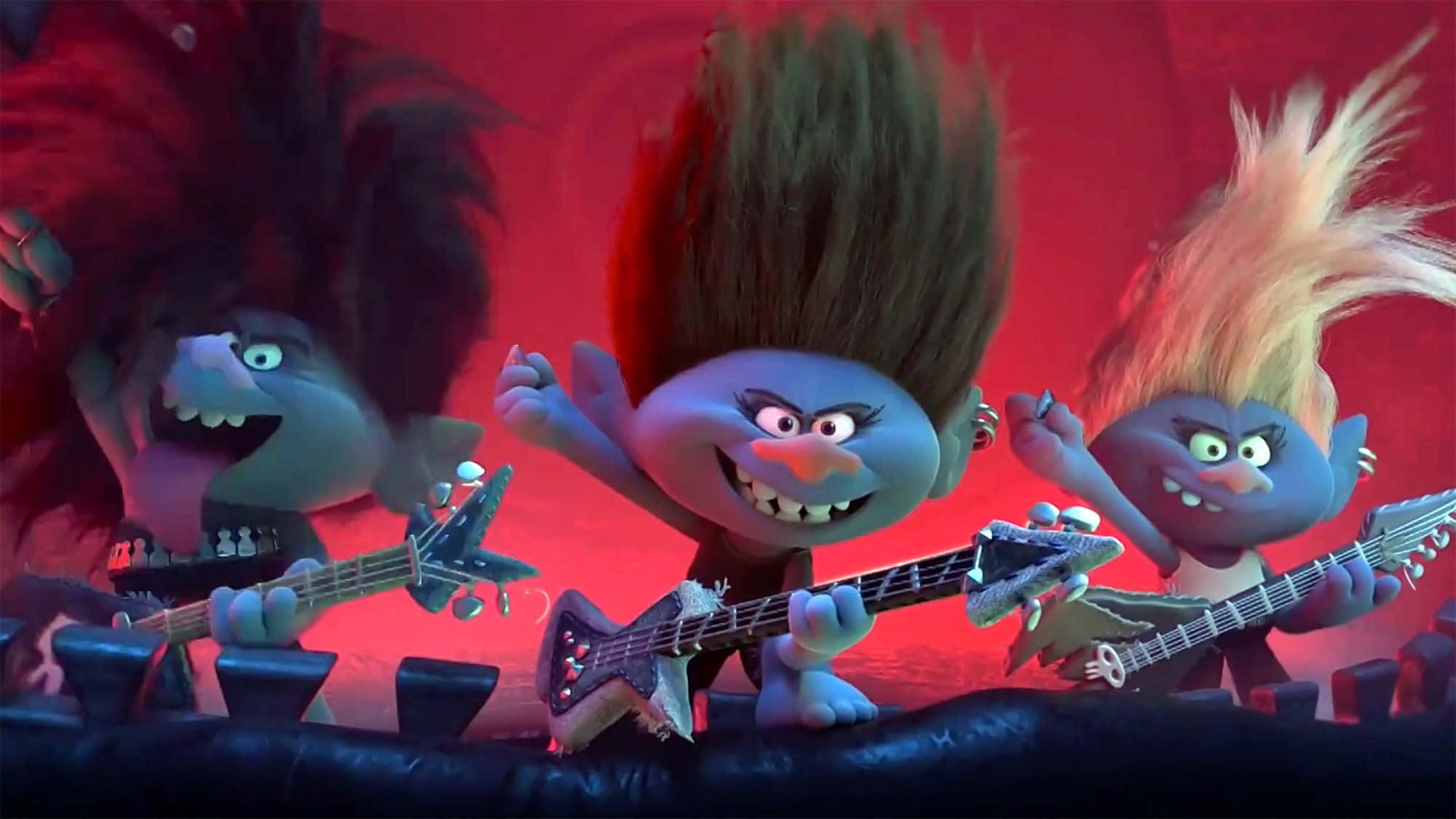 Trolls World Tour 桌布 壁紙 — 三個動畫巨魔，頭髮凌亂，在紅色舞台燈光下帶著強烈表情彈奏電吉他。