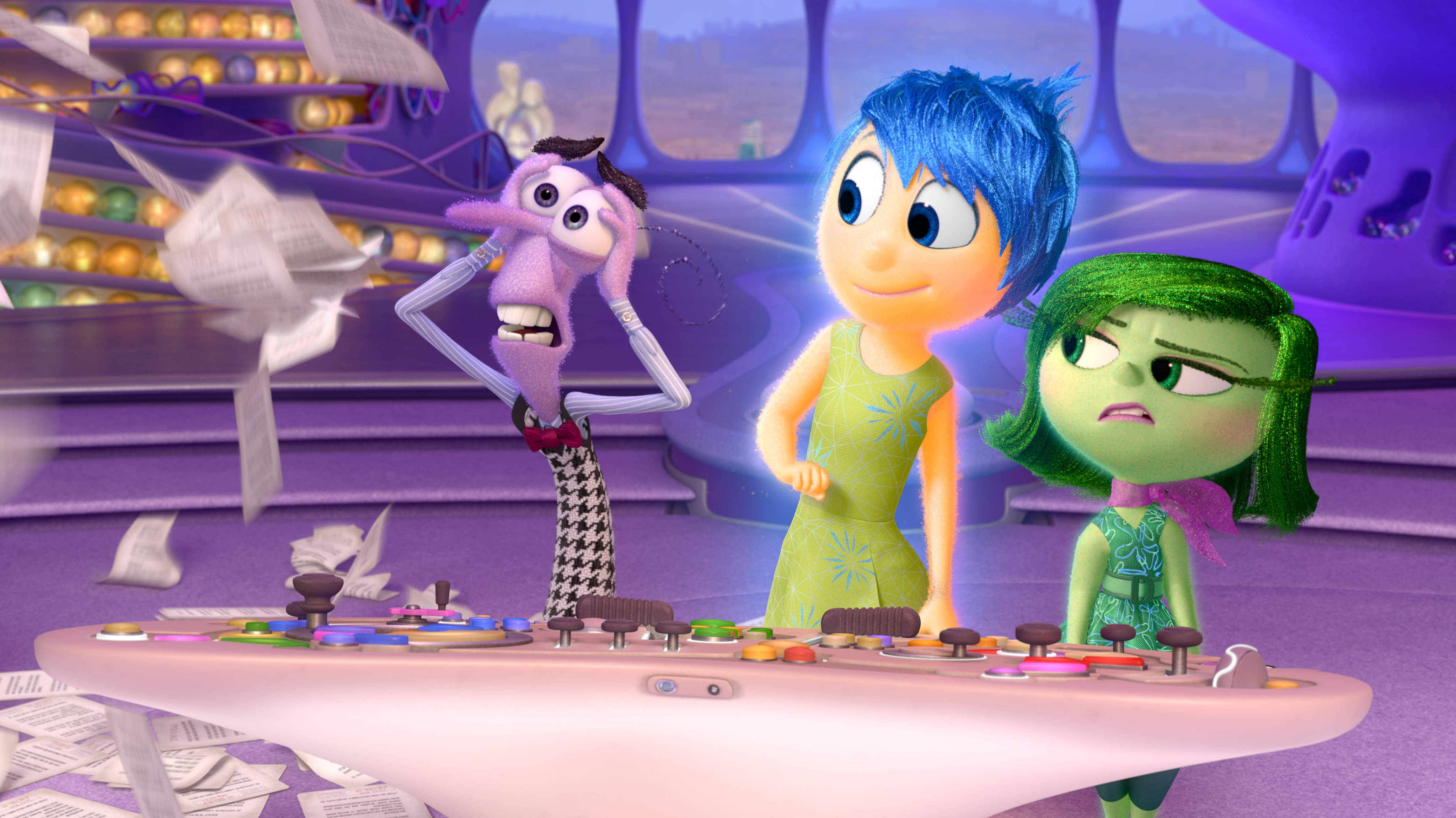 Joy Inside Out 桌布 壁紙 — 三個動畫情緒角色站在一個紫色未來感房間的控制面板前，房間裡充滿了漂浮的紙張。