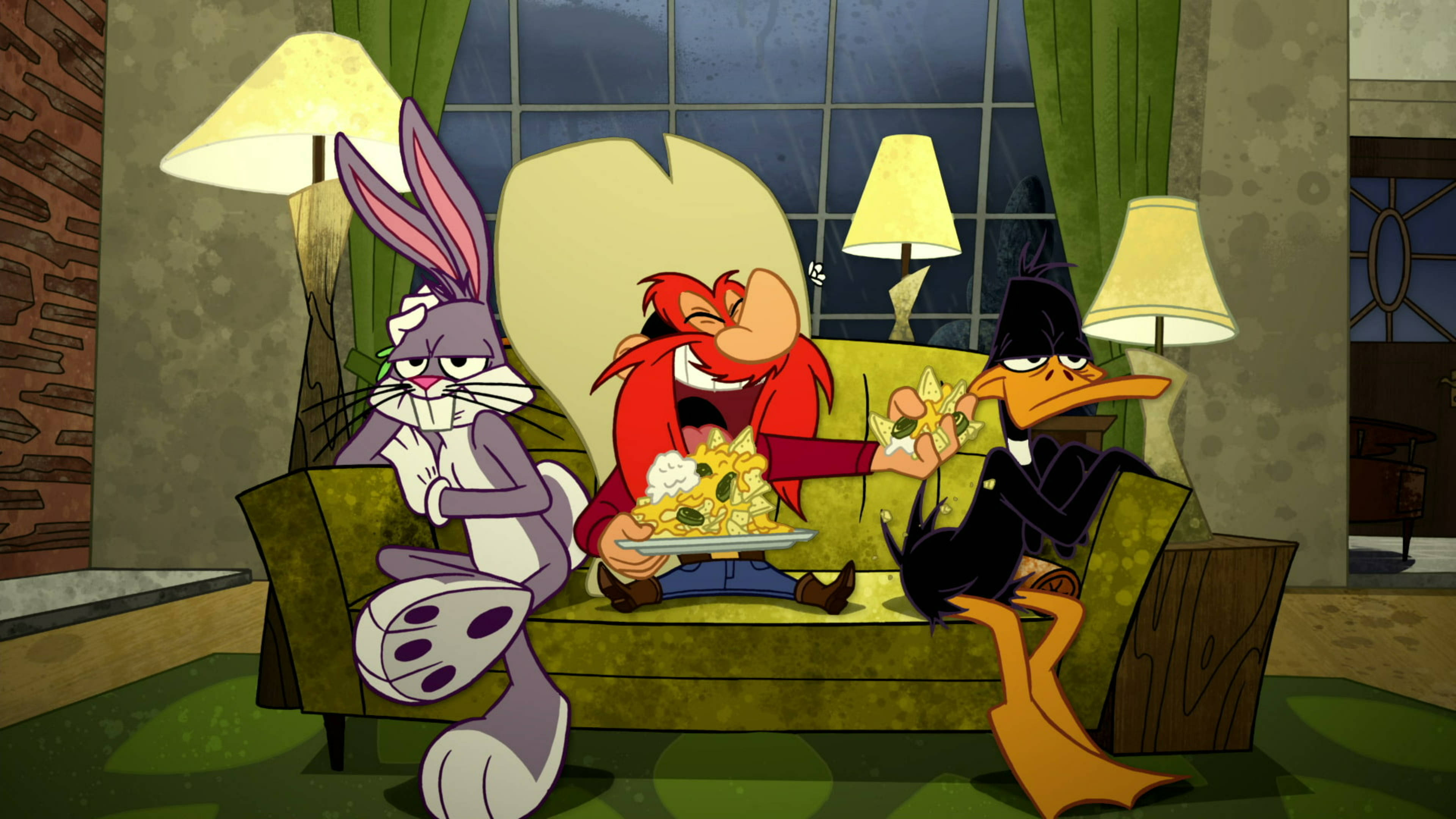 Yosemite Sam 桌布 壁紙 — 三個動畫角色坐在昏暗房間的綠色沙發上，有燈和窗簾，分享一盤義大利麵。