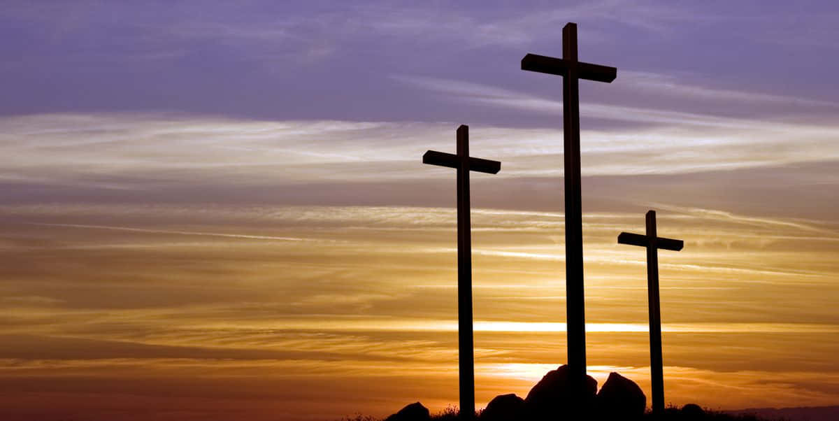 Lent 桌布 壁紙 — 三個十字架在充滿活力的日落天空背景下呈現剪影，天空中有橙色和紫色的條紋雲彩。