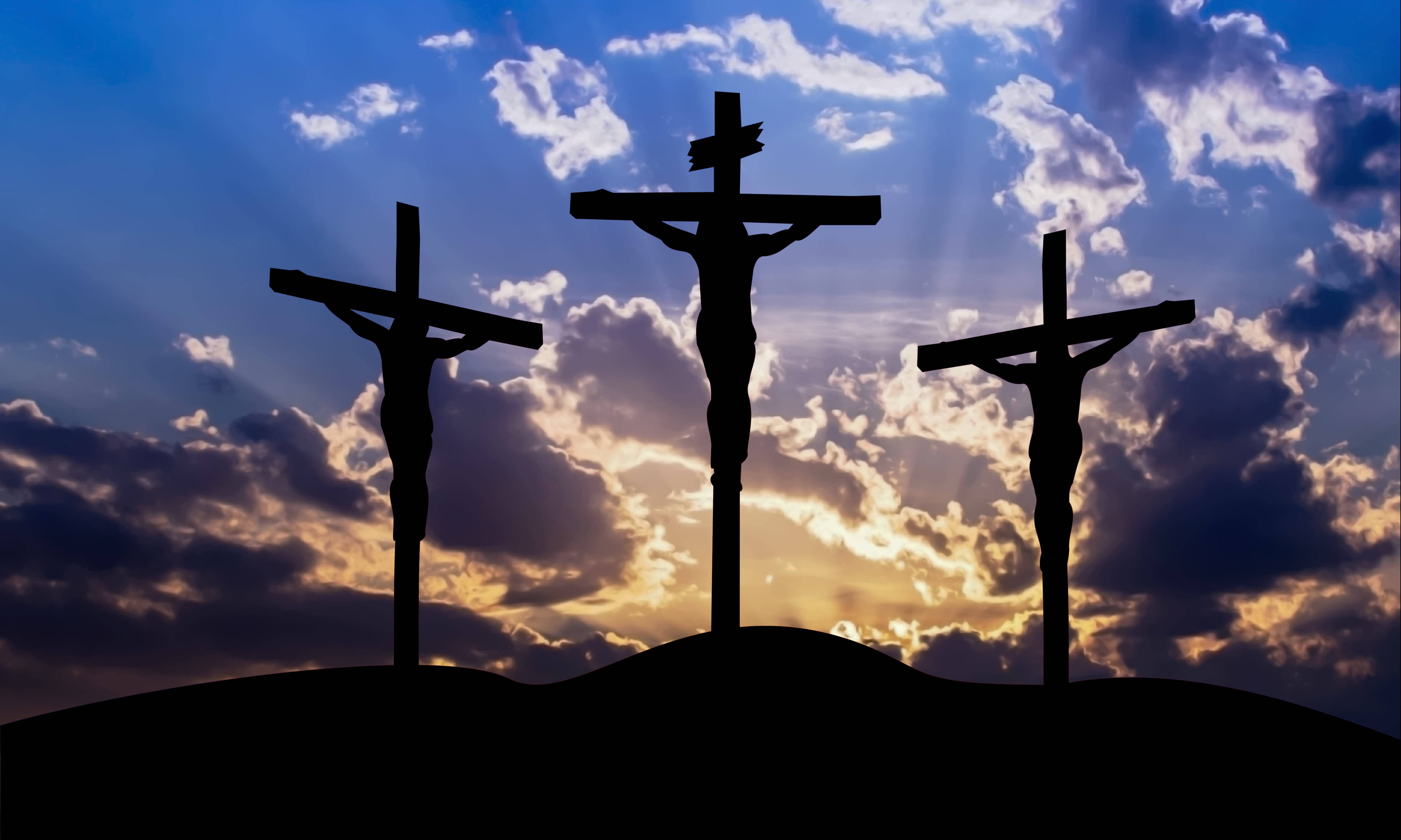 Christ 桌布 壁紙 — 三個十字架在戲劇性的日落天空背景下形成剪影，燦爛的陽光穿透雲層。