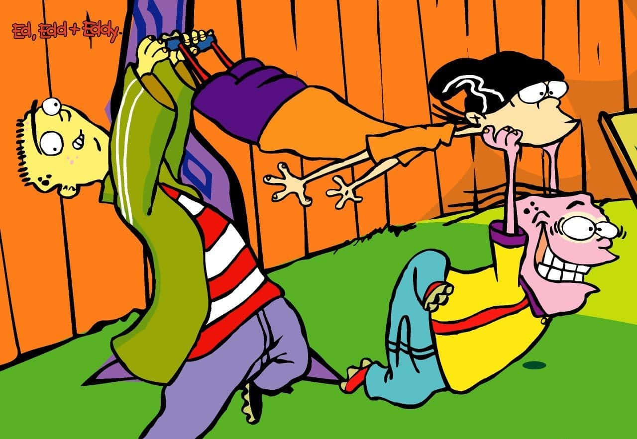 Cartoon 桌布 壁紙 — 三個卡通小孩在橙色木柵欄前的綠色草坪上嬉戲摔跤。