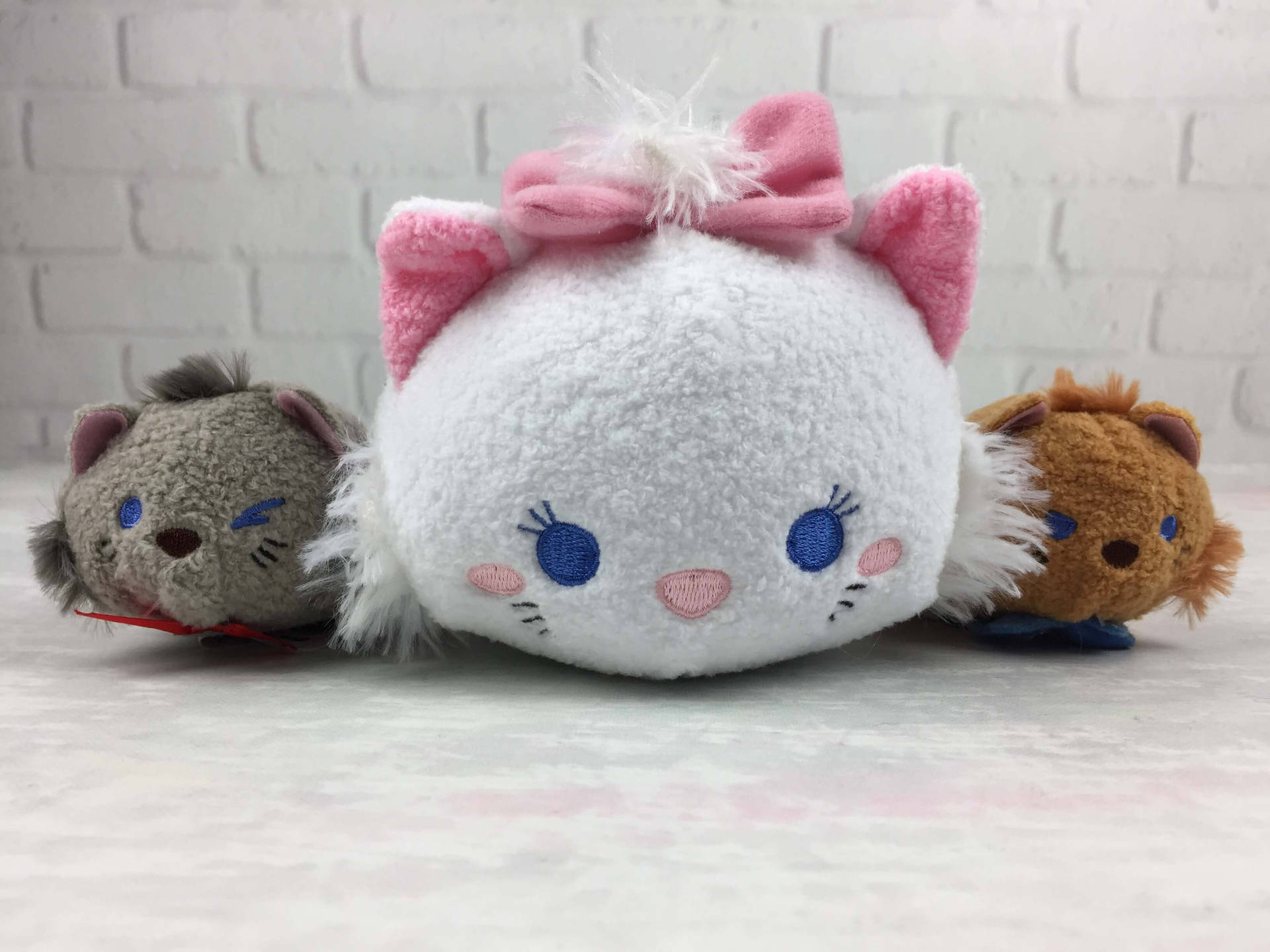 三個Tsum Tsum毛絨玩具，包括一隻戴粉紅色蝴蝶結的白貓。 — Tsum tsum 壁紙