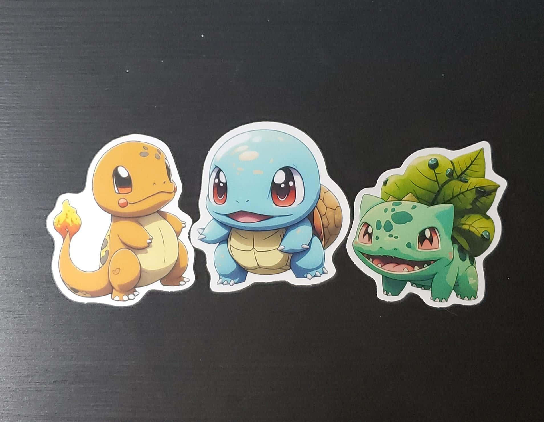 Pokemon Stickers 桌布 壁紙 — 三個可愛的寶可夢貼紙：小火龍、傑尼龜和妙蛙種子，排列在深色紋理表面上。