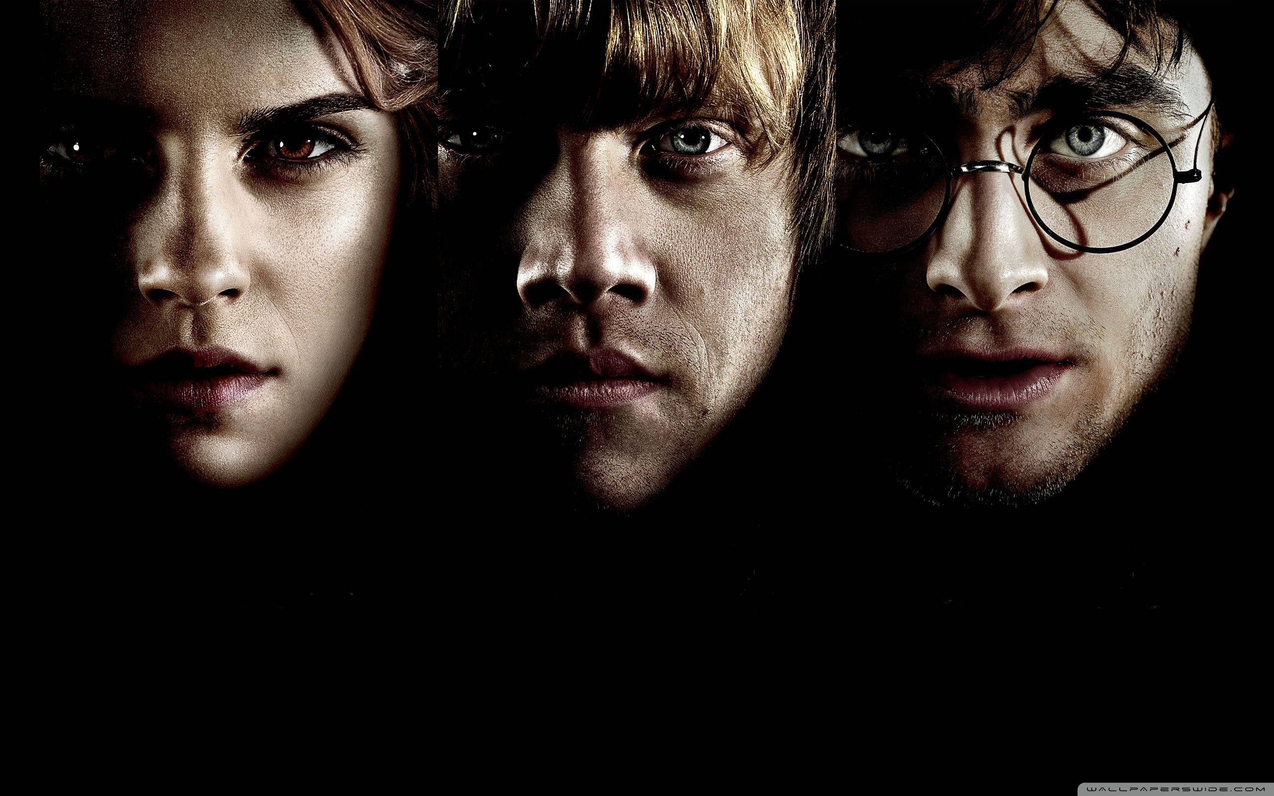 Hermione 桌布 壁紙 — 三個哈利波特、妙麗和榮恩的強烈面孔，在黑暗背景下被照亮。
