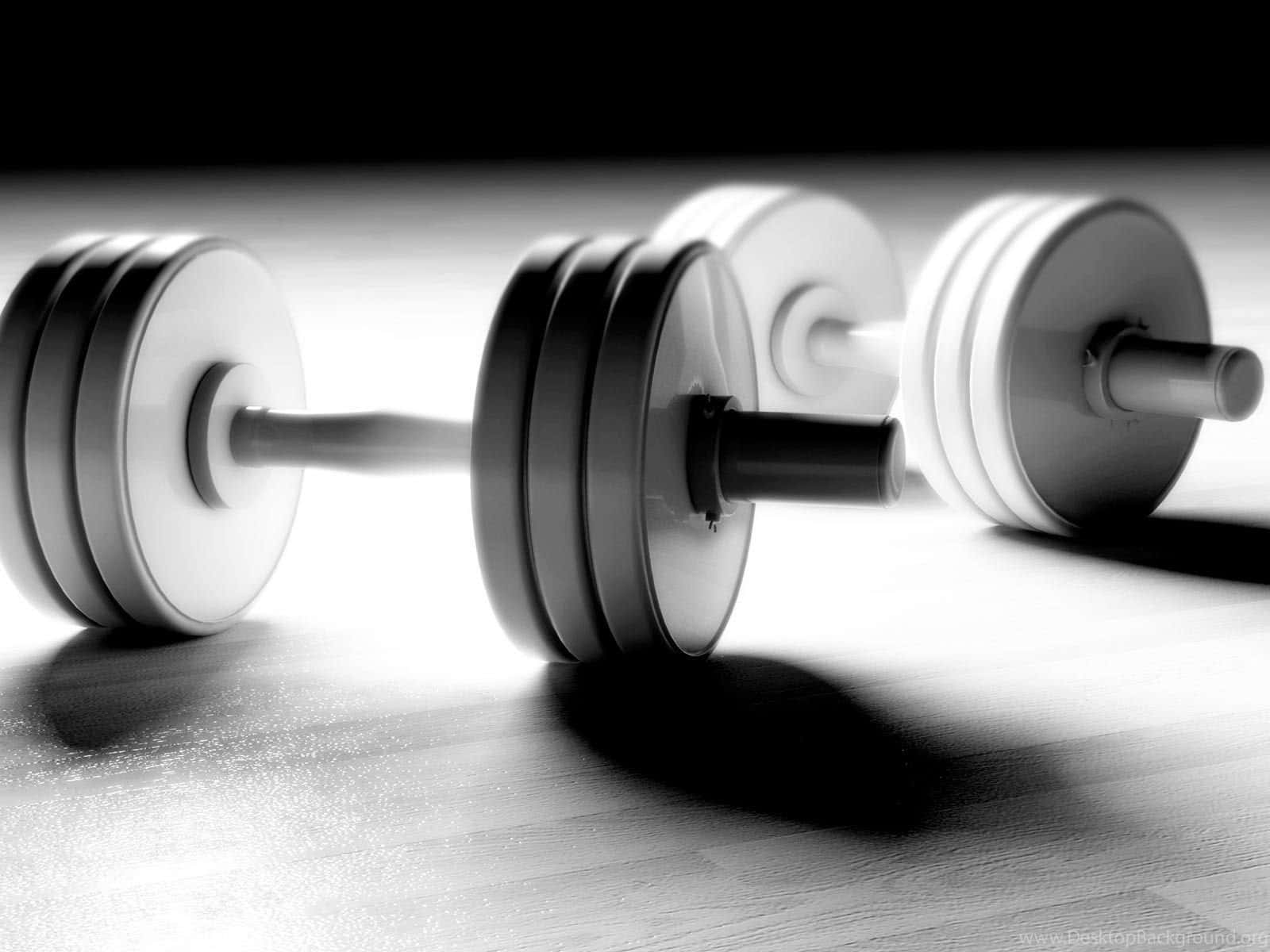 Workout 桌布 壁紙 — 三個啞鈴排成一排放在木地板上，在戲劇性的黑白燈光下。