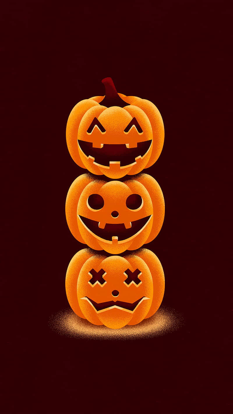 Pumpkin 桌布 壁紙 — 三個堆疊的南瓜燈籠，帶有不同雕刻的臉孔，在深栗色背景上溫暖地發光。