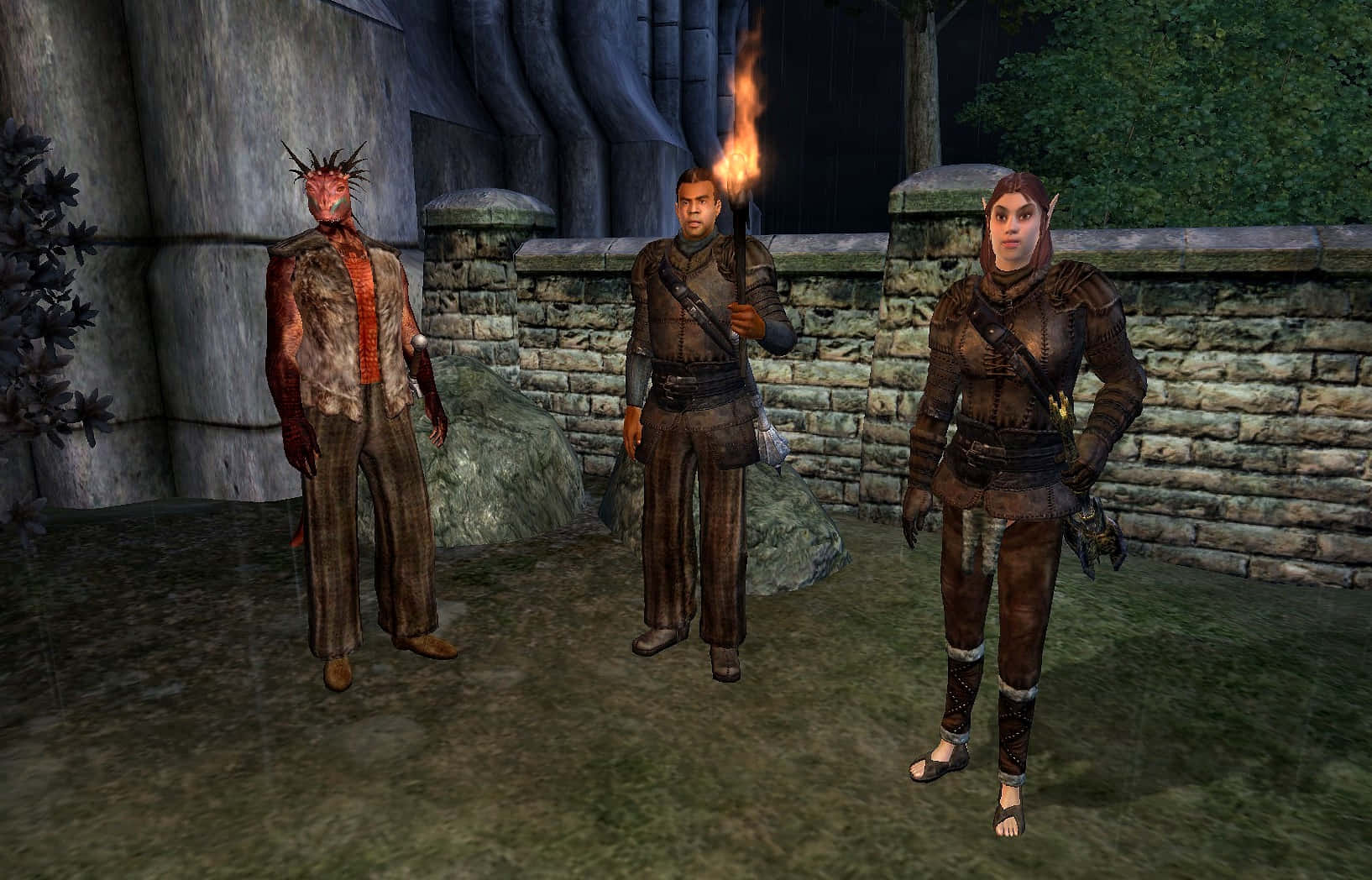 Thieves Guild 桌布 壁紙 — 三個奇幻角色站在昏暗的石頭庭院中，其中一人手持燃燒的火把，將溫暖的光芒投射在他們裝甲的身影上。