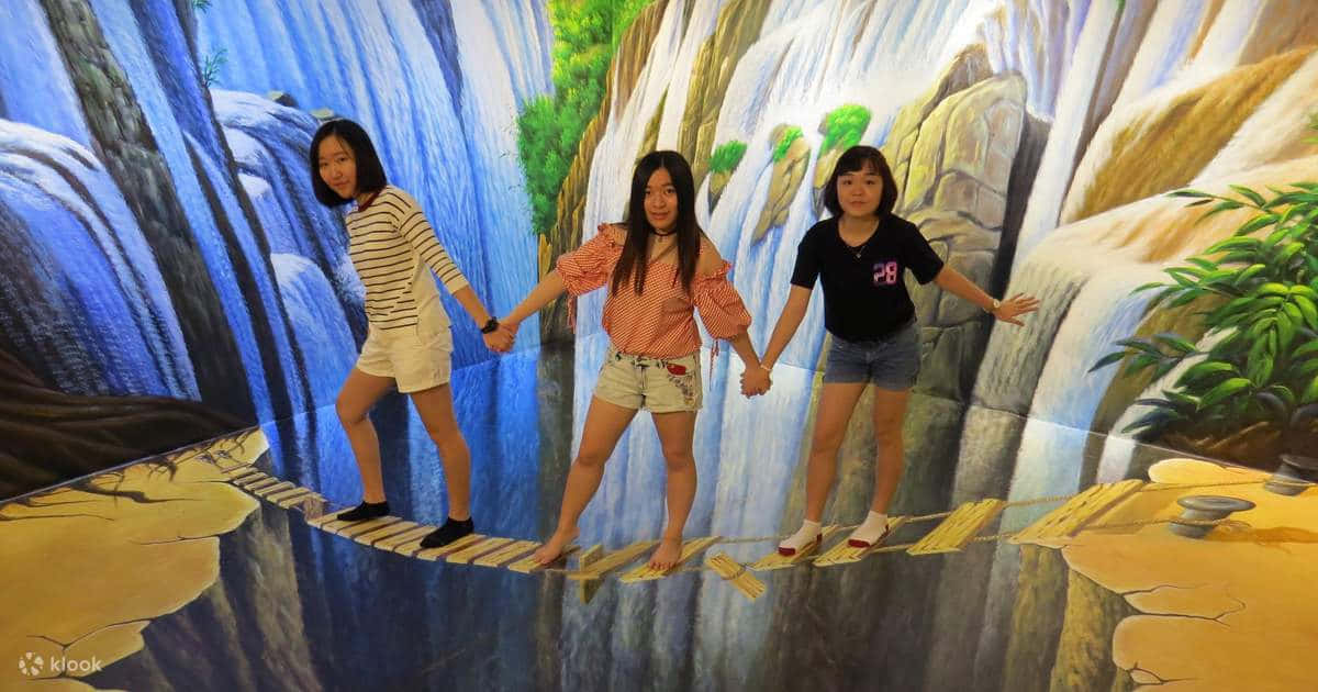 3D 桌布 壁紙 — 三個女孩手牽手，走過沉浸式藝術裝置中瀑布上方繪製的3D橋樑。