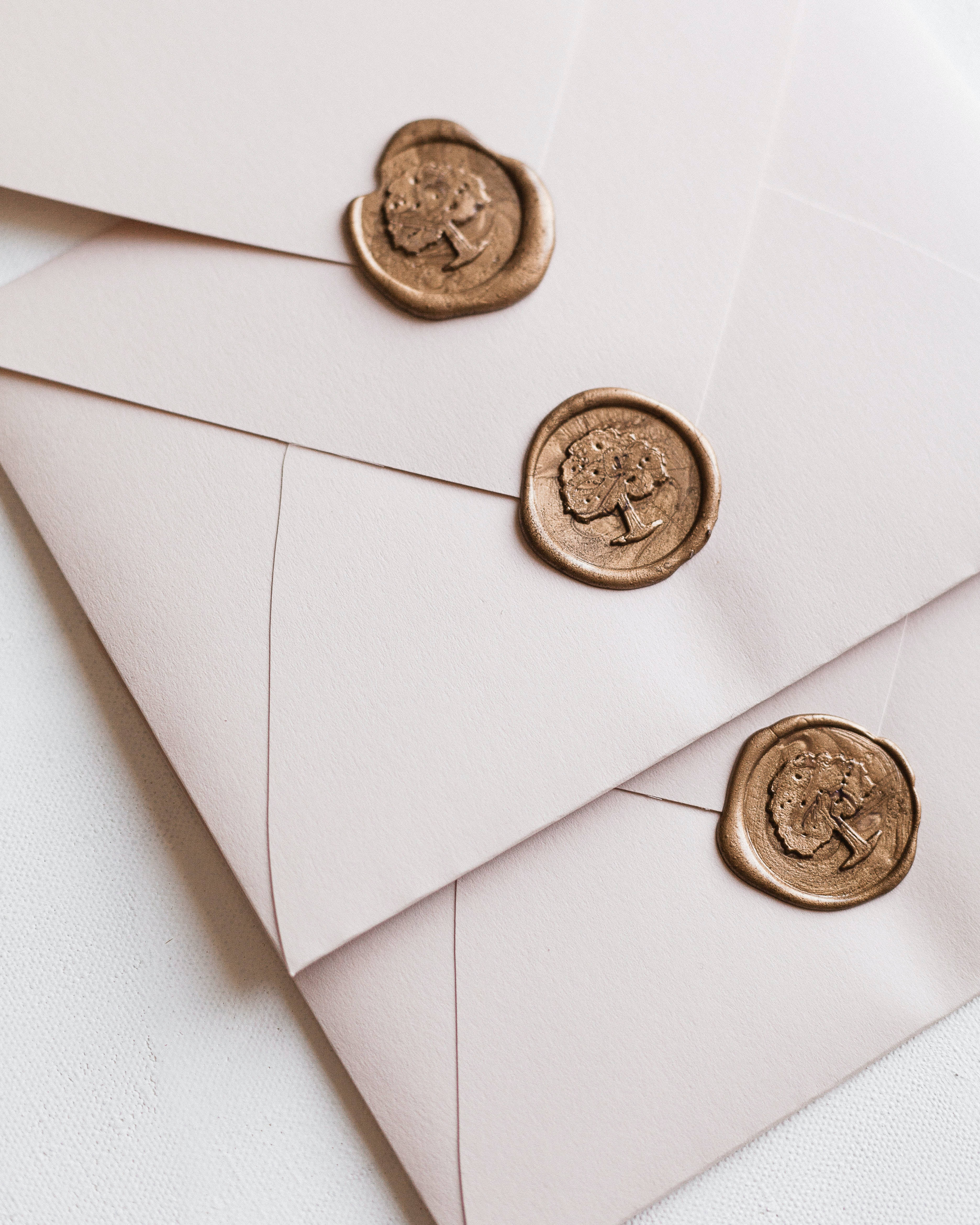 Wedding Card 桌布 壁紙 — 三個奶油色信封，以帶有樹木圖案的金色火漆封緘，整齊地斜疊在一起。