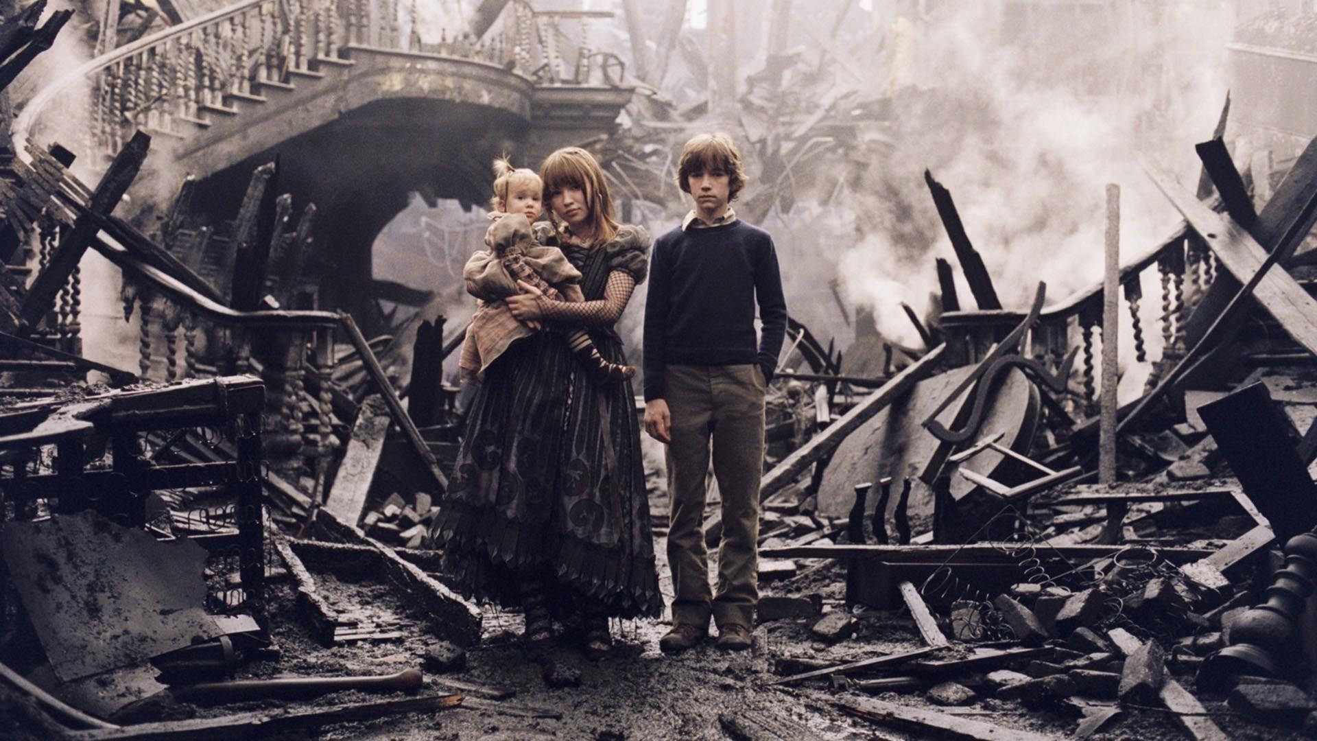 電影動圖 桌布 壁紙 — 三個孩子莊嚴地站在被毀建築物的煙霧瀰漫廢墟中，有斷裂的樓梯和散落的碎片。