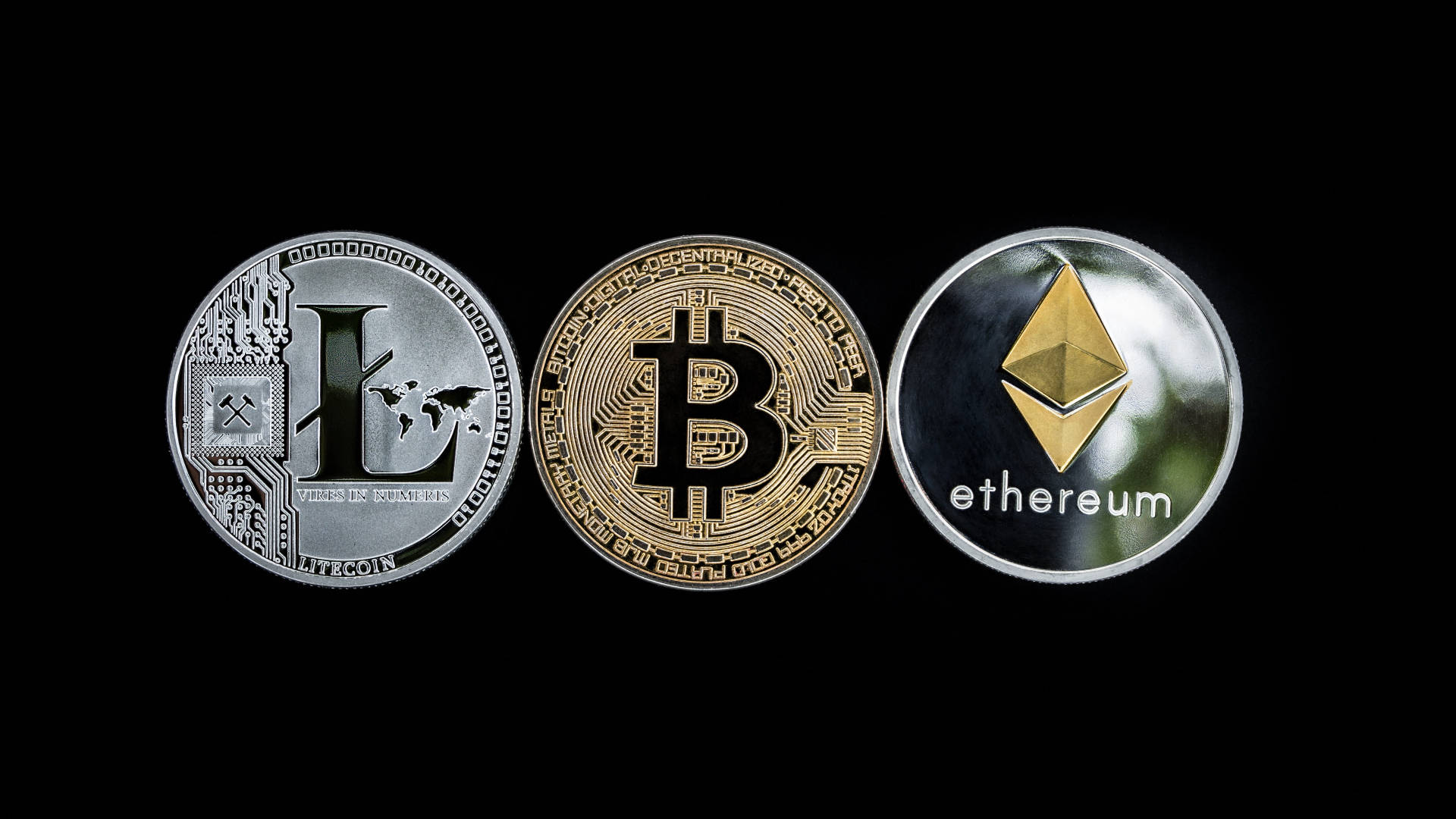以太坊 桌布 壁紙 — 三個實體加密貨幣硬幣Litecoin Bitcoin和Ethereum在黑色背景上顯示，帶有金屬反射。