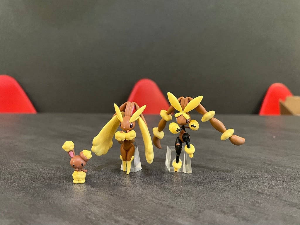 小孩動圖 桌布 壁紙 — 三個寶可夢公仔排成一排，放在一張深色桌子上，背景有紅色椅子。