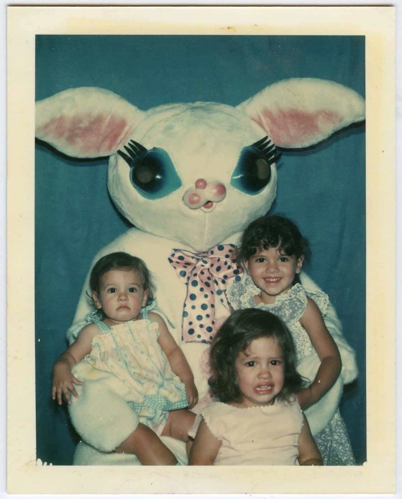 Creepy Easter Bunny 桌布 壁紙 — 三個小孩與一隻巨大的白色兔子吉祥物在藍色背景前擺姿勢的復古照片。