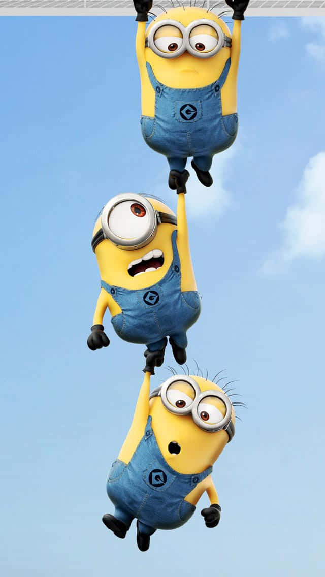 Minion 桌布 壁紙 — 三個小小兵倒掛成一條鏈，襯托著晴朗的藍天和 fluffy 的白雲。