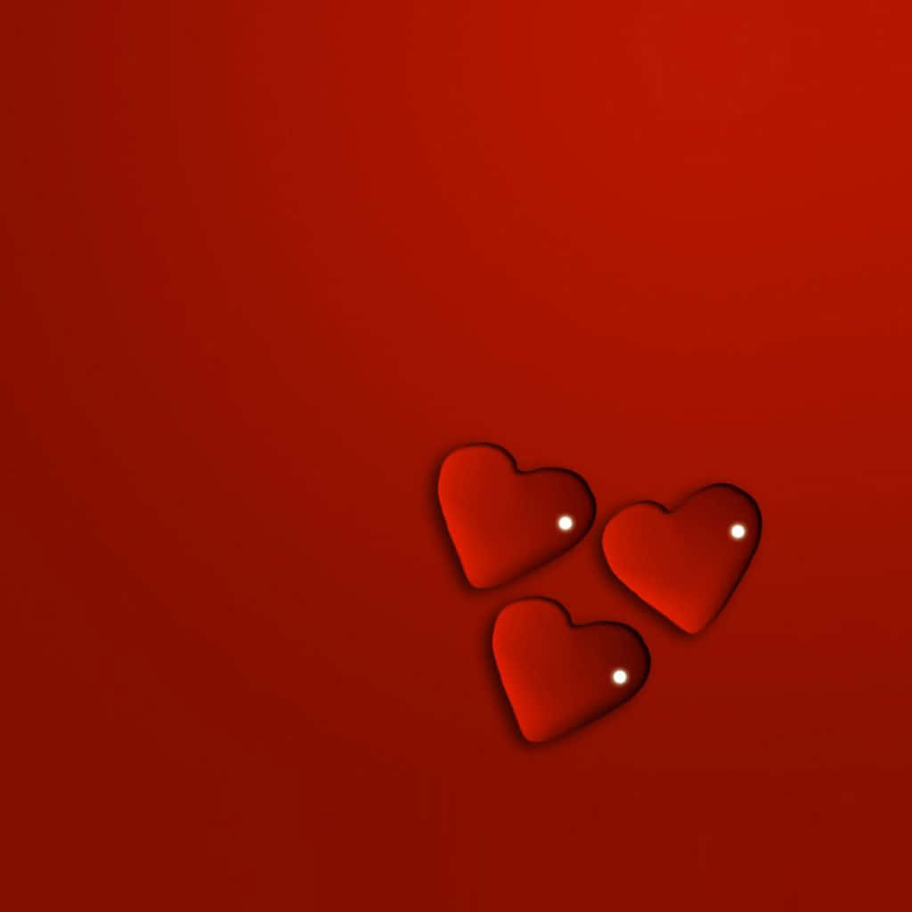 Red Heart 桌布 壁紙 — 三個帶有白色高光的亮面紅色愛心漂浮在深紅色漸層背景上。