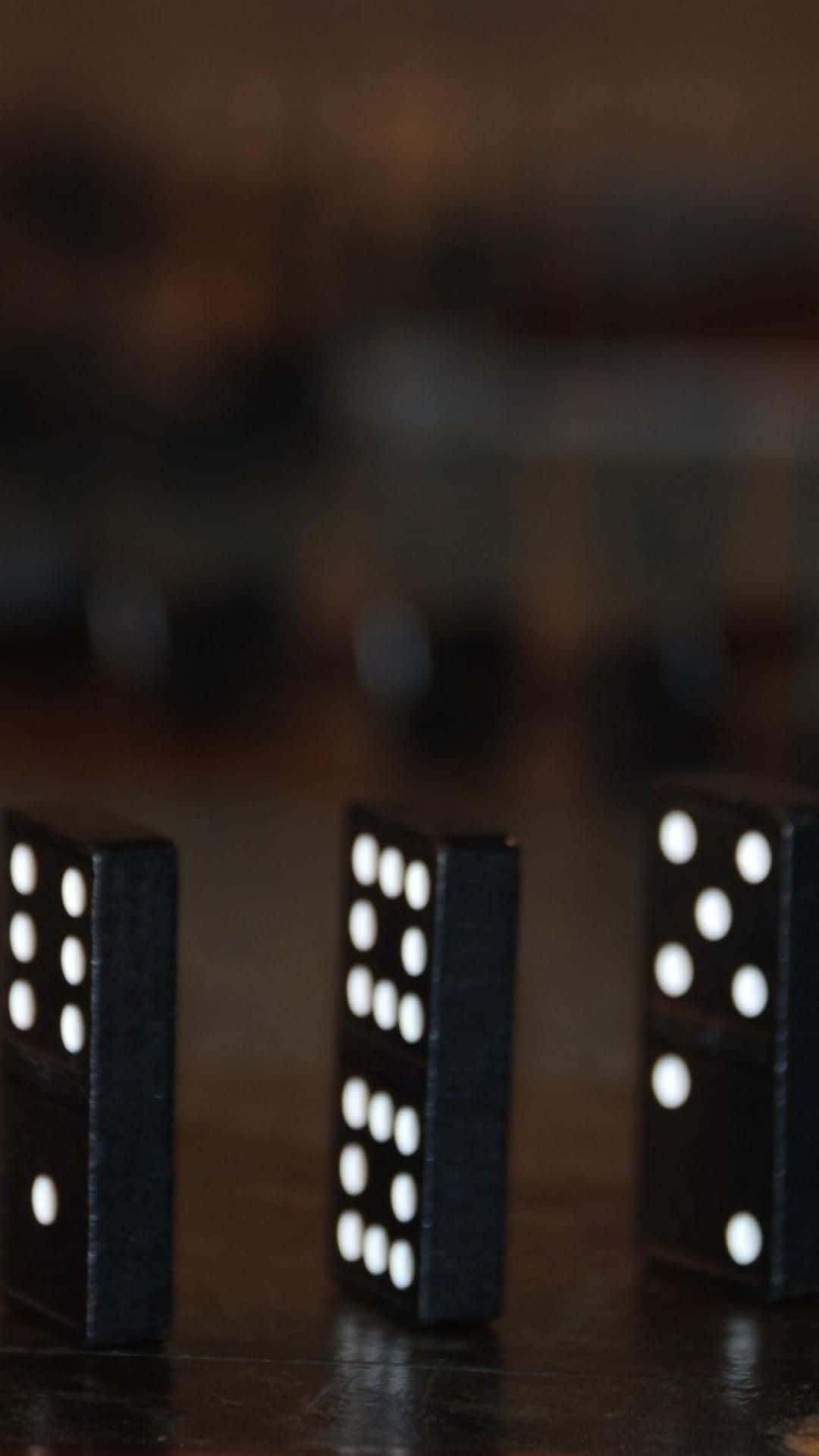 Domino 桌布 壁紙 — 三個帶有白點的黑色的多米諾骨牌直立於深色木質表面上，景深較淺。