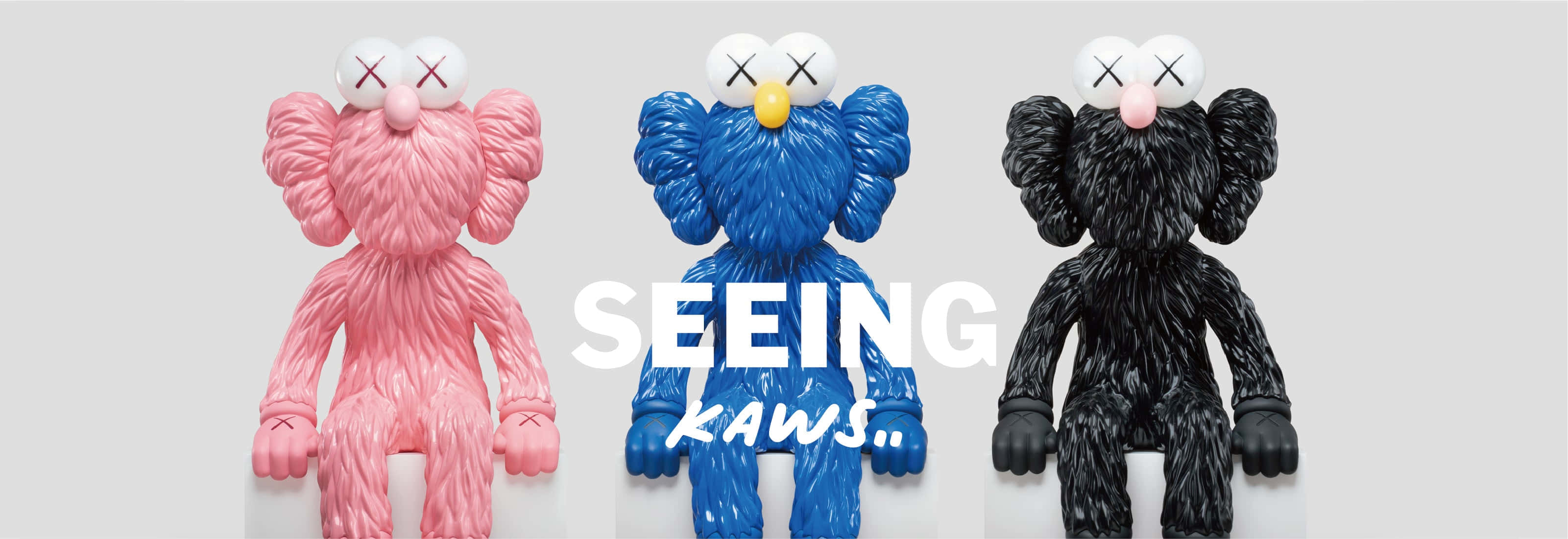 KAWS 桌布 壁紙 — 三個帶有紋理的KAWS毛絨公仔，分別是粉紅色、藍色和黑色，並排站在純灰色背景上，配有粗體白色文字。