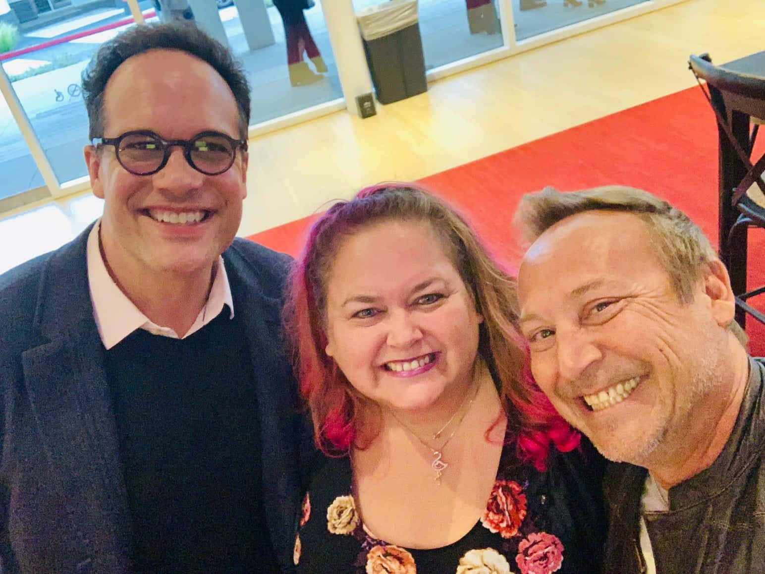 Diedrich Bader 桌布 壁紙 — 三個微笑的人在室內近距離擺姿勢自拍，背景是紅地毯和玻璃門。