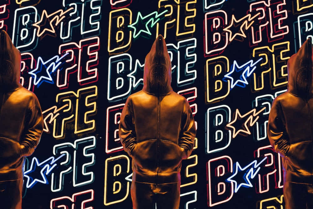 Bape 動態 桌布 壁紙 — 三個戴帽人物站在一面充滿活力的霓虹牆前，牆上重複顯示著電光色的Bape標誌。