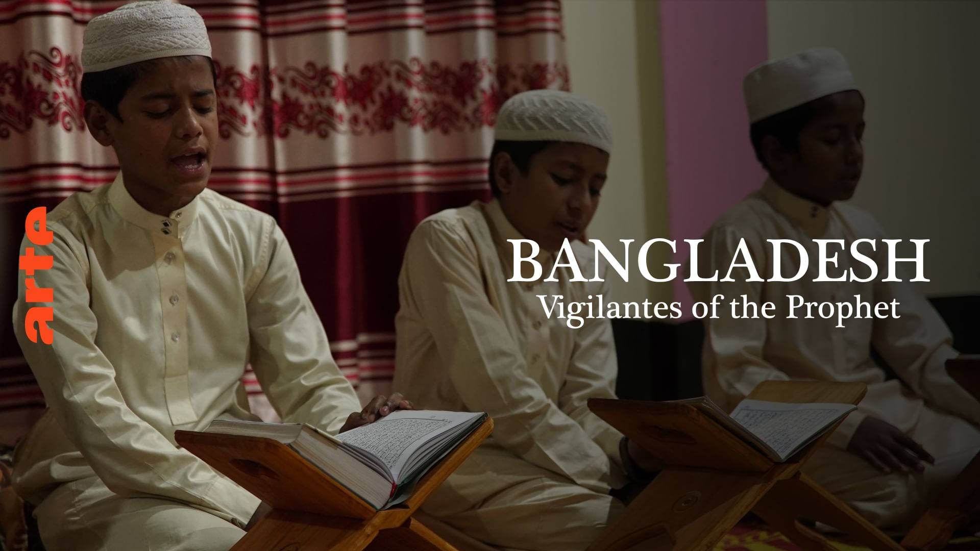 Bangladesh 桌布 壁紙 — 三個戴白帽穿白袍的小男孩在溫暖燈光下，莊嚴地坐在室內閱讀木架上的書本。