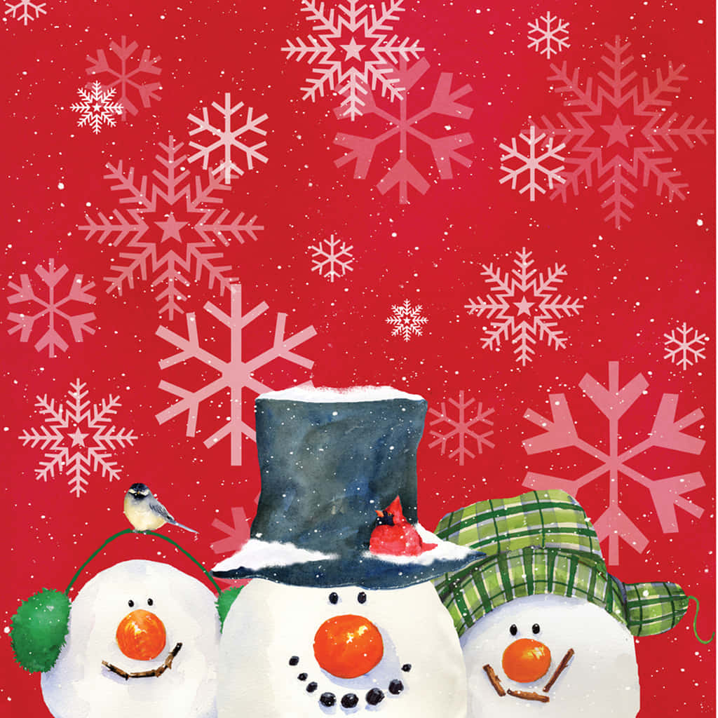 iPad Christmas 桌布 壁紙 — 三個戴著胡蘿蔔鼻子和帽子的快樂雪人站在充滿飄落雪花的鮮紅色背景前。