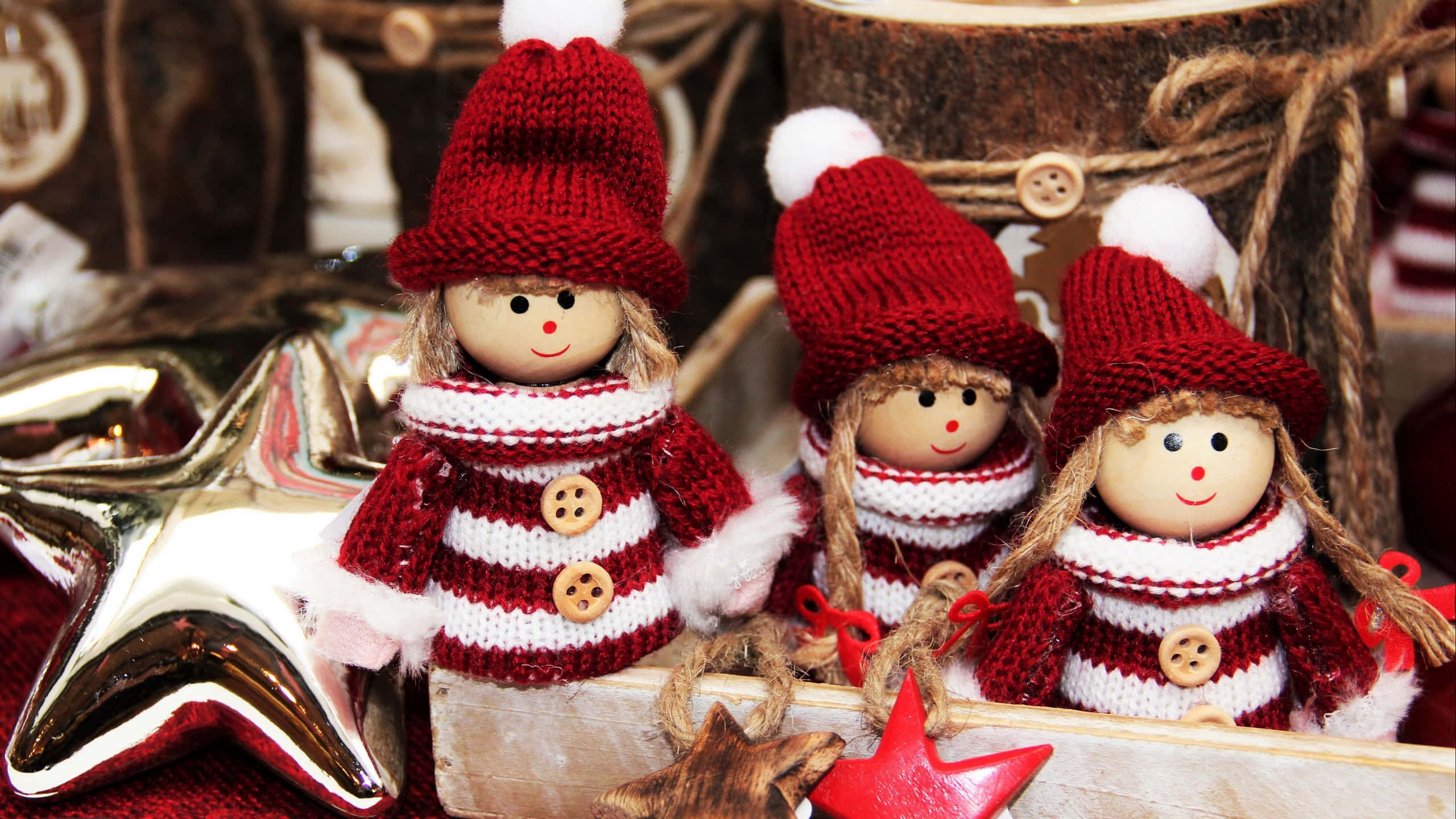 Christmas Elf 桌布 壁紙 — 三個手織聖誕公仔，戴紅色帽子和條紋毛衣，坐在一個質樸的木托盤上，旁邊有閃亮的星星。