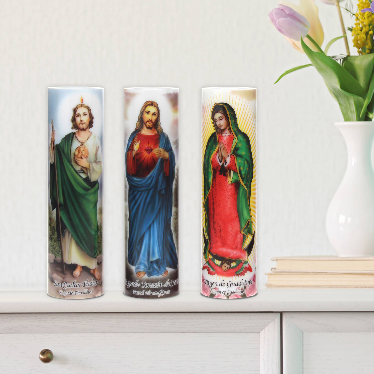 religion 桌布 壁紙 — 三個描繪聖猶達達陡、耶穌聖心和瓜達盧佩聖母的宗教燭台，放在一個白色架子上，旁邊有一個鬱金香花瓶。
