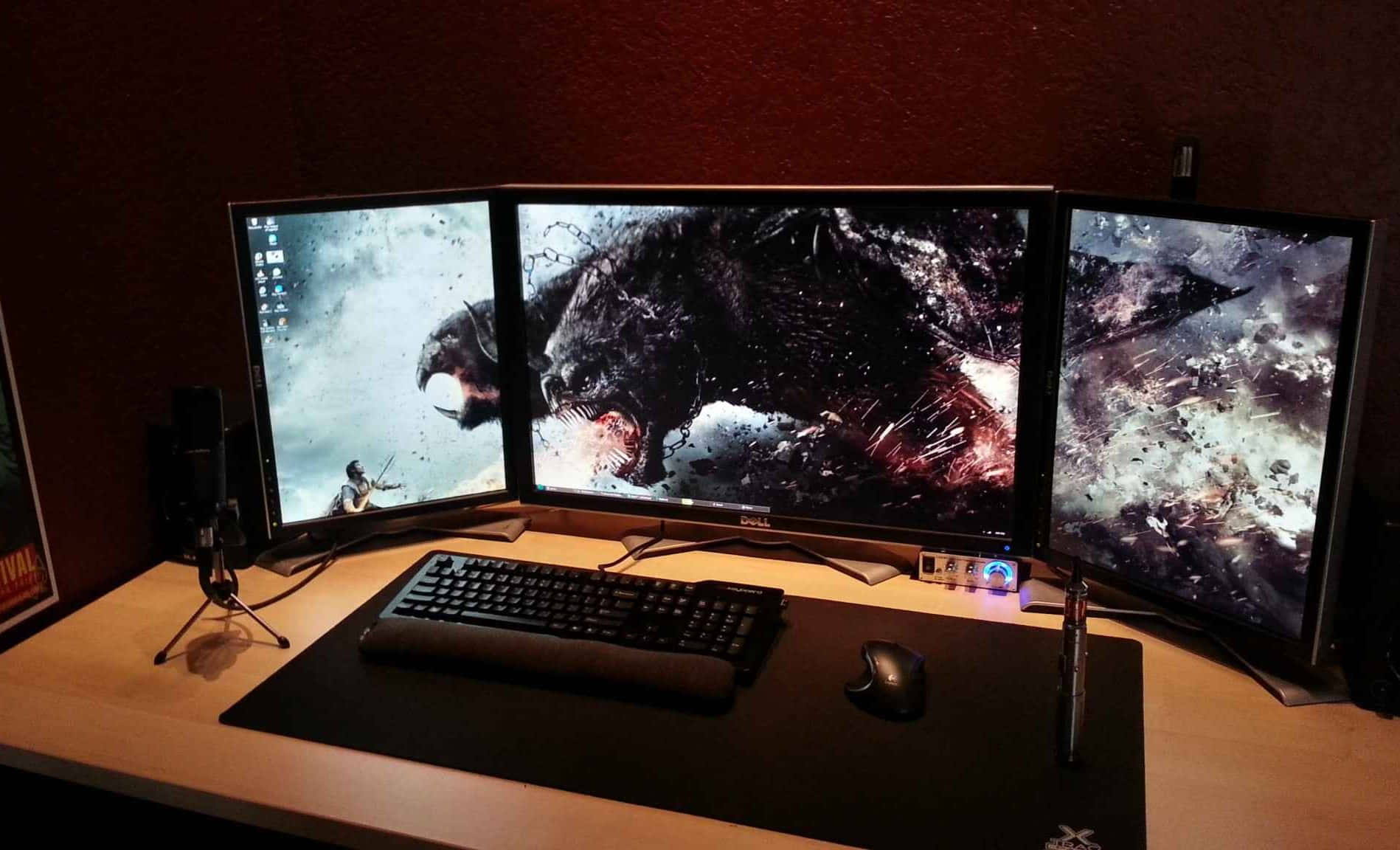 Gaming Setup 桌布 壁紙 — 三個曲面顯示器在昏暗的遊戲桌上顯示一個黑暗奇幻遊戲場景，有咆哮的野獸和戰士，背景是暴風雨的天空。