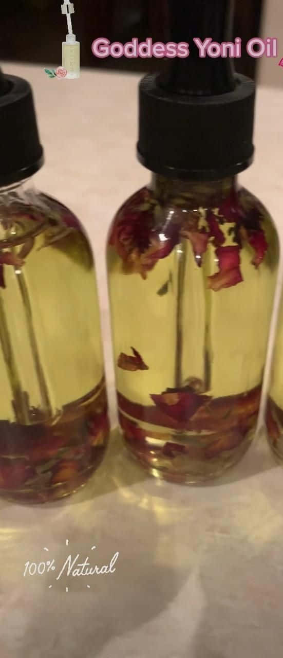 Rose Oil 桌布 壁紙 — 三個琥珀色瓶子裝滿金色油和漂浮的紅玫瑰花瓣，放在淺色檯面上。