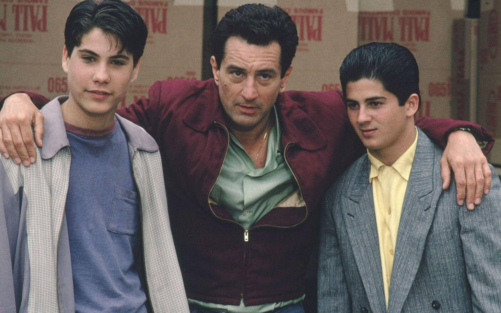 goodfellas 桌布 壁紙 — 三個男人在倉庫裡緊密地擺姿勢，手臂搭在彼此的肩膀上，背景是堆疊的紙箱。