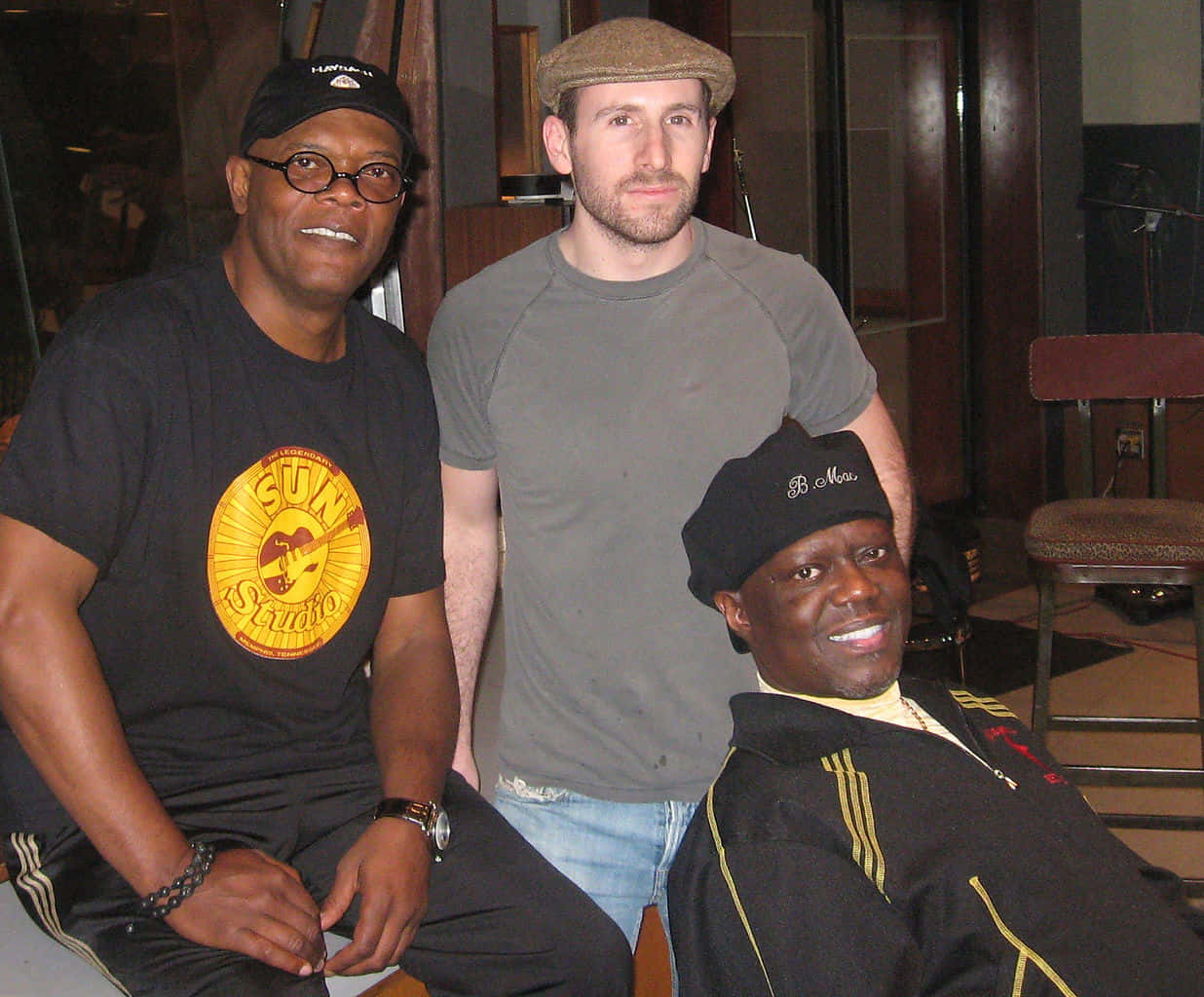 Bernie Mac 桌布 壁紙 — 三個男人在室內一起擺姿勢，一個穿著太陽工作室T恤，另一個戴著平頂帽和牛仔褲，第三個戴著黑色無邊帽和夾克。