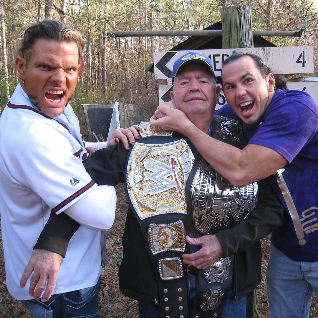 WWE 桌布 壁紙 — 三個男人在樹林地區擺姿勢，手持WWE冠軍腰帶，一個尖叫，一個咧嘴笑，一個微笑