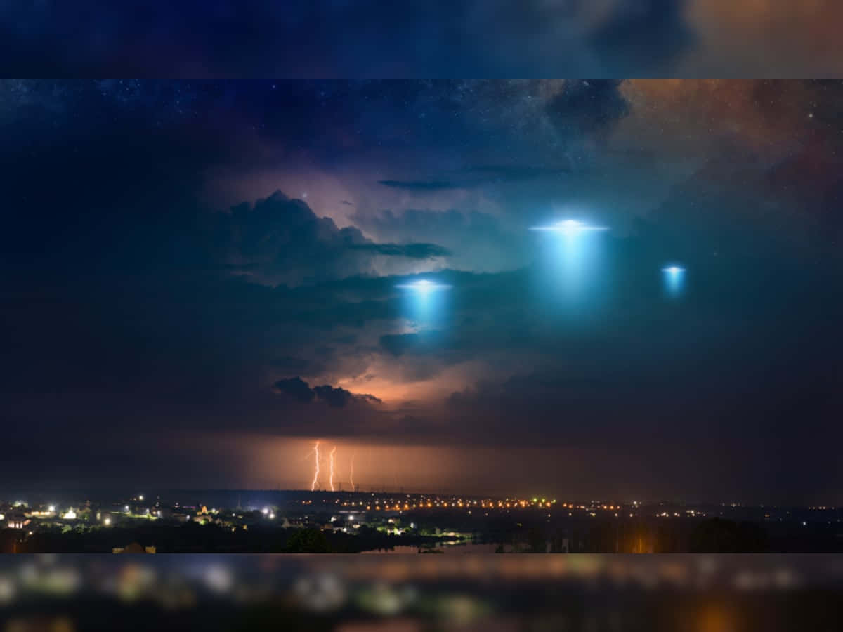 幽浮 桌布 壁紙 — 三個發光的UFO在閃電交加、星空燦爛的夜晚，盤旋於暴風雨的城市景觀之上。