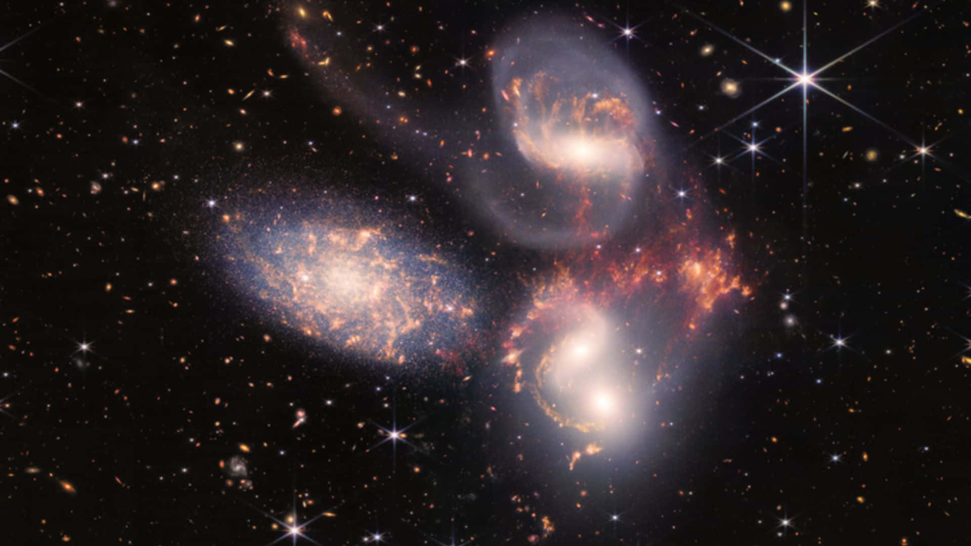 銀河 桌布 壁紙 — 三個發光的螺旋星系在宇宙舞蹈中碰撞，背景是閃爍的星星和宇宙塵埃的星場。