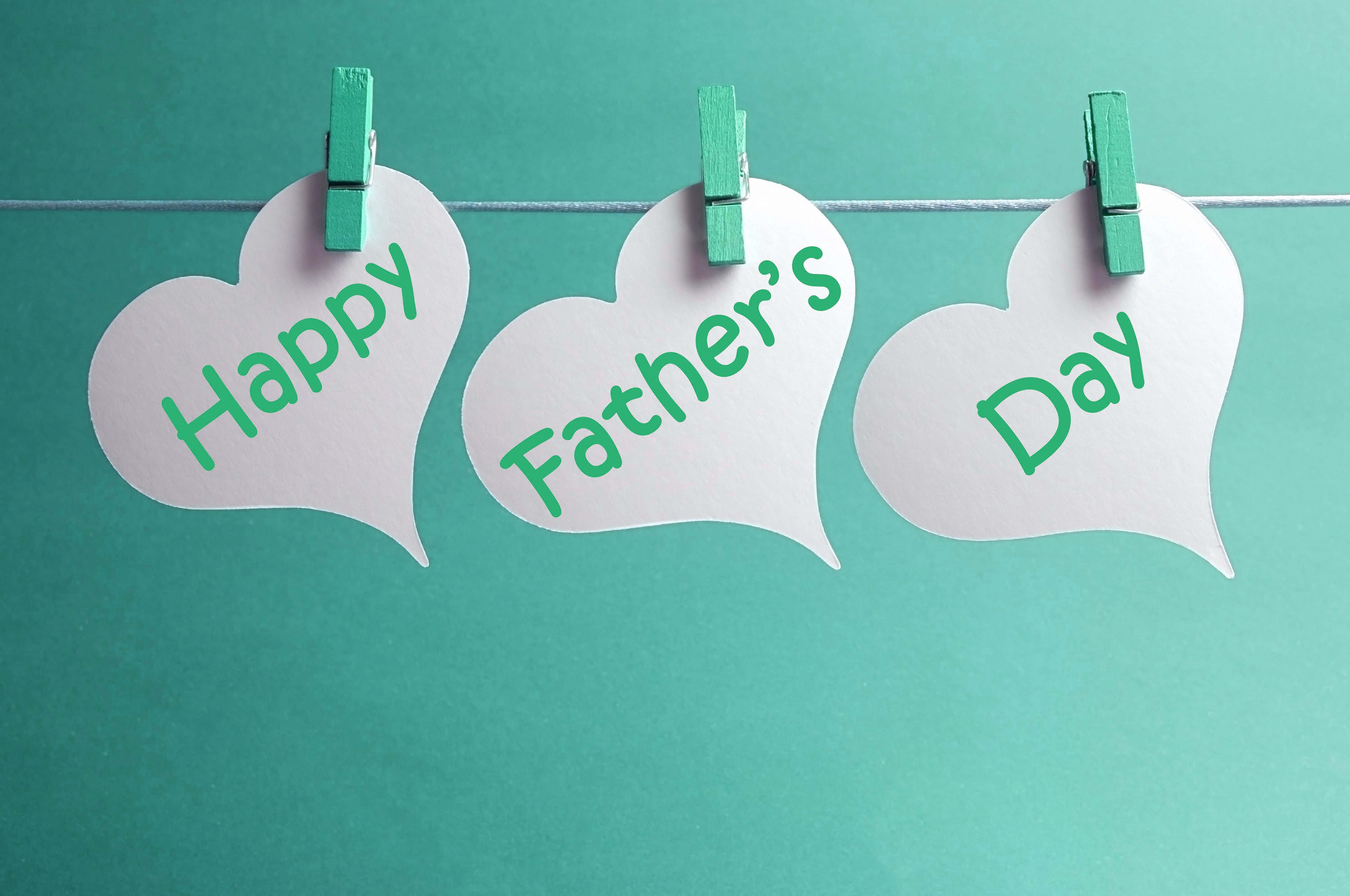 父親節 桌布 壁紙 — 三個白色心形紙牌，上面有綠色文字寫著「Happy Father's Day」，用綠色衣夾掛在一條線上，背景為藍綠色。