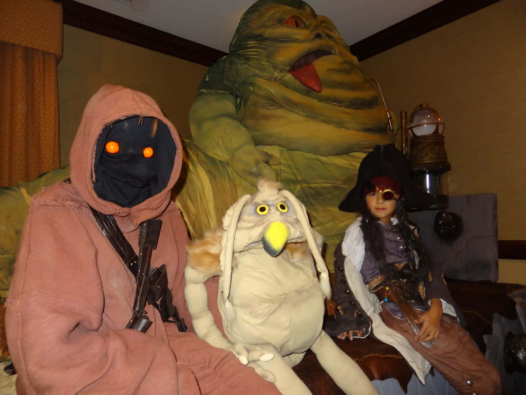 jabba the hutt 桌布 壁紙 — 三個穿著戲服的角色，包括一個賈巴·赫特人偶和一個穿著海盜裝備的孩子，在室內一起擺姿勢。